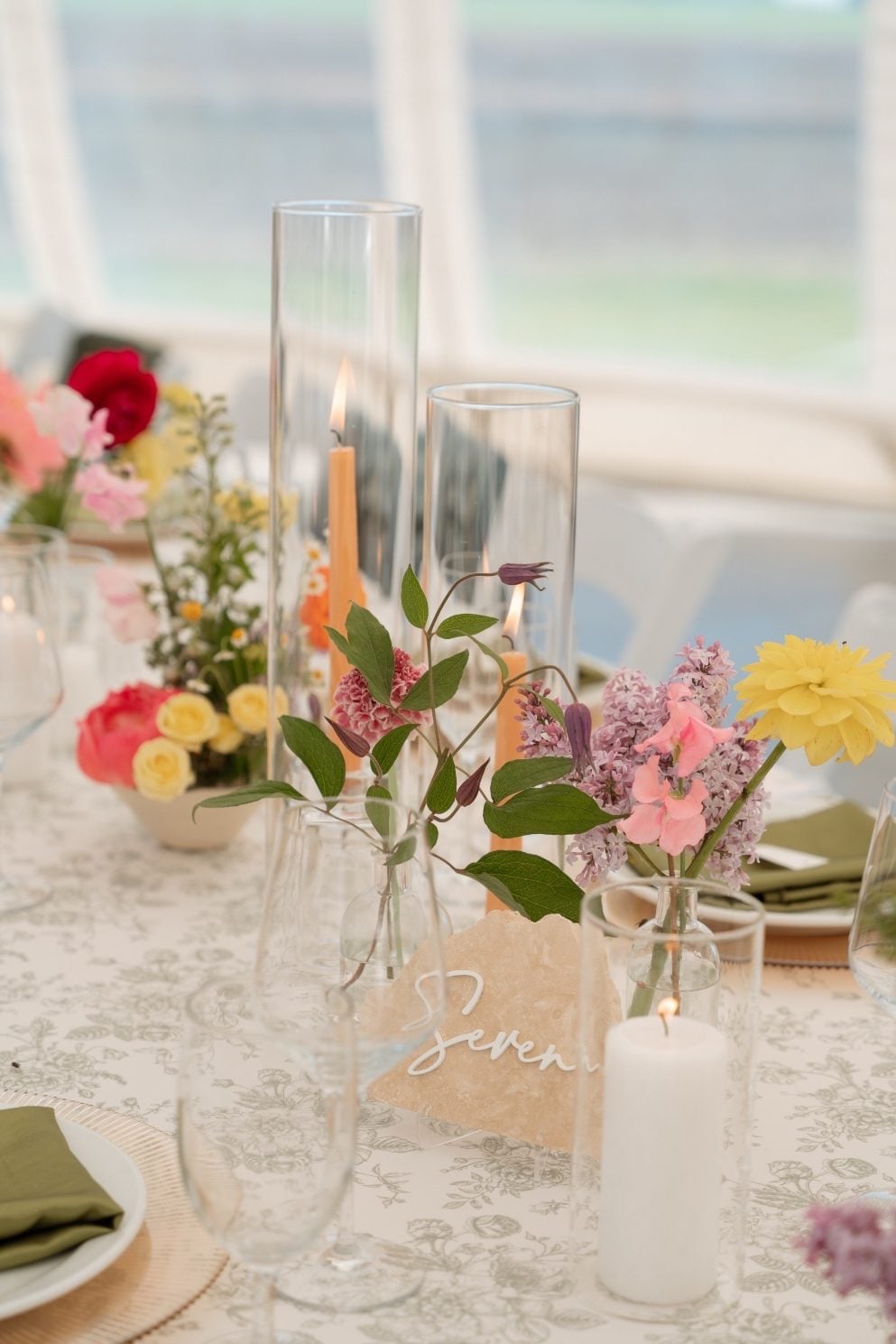 Colourful Ikebana Centrepieces Harvest style guest tables with ikebana centrepieces placed between cylinder vases with peach taper candles.