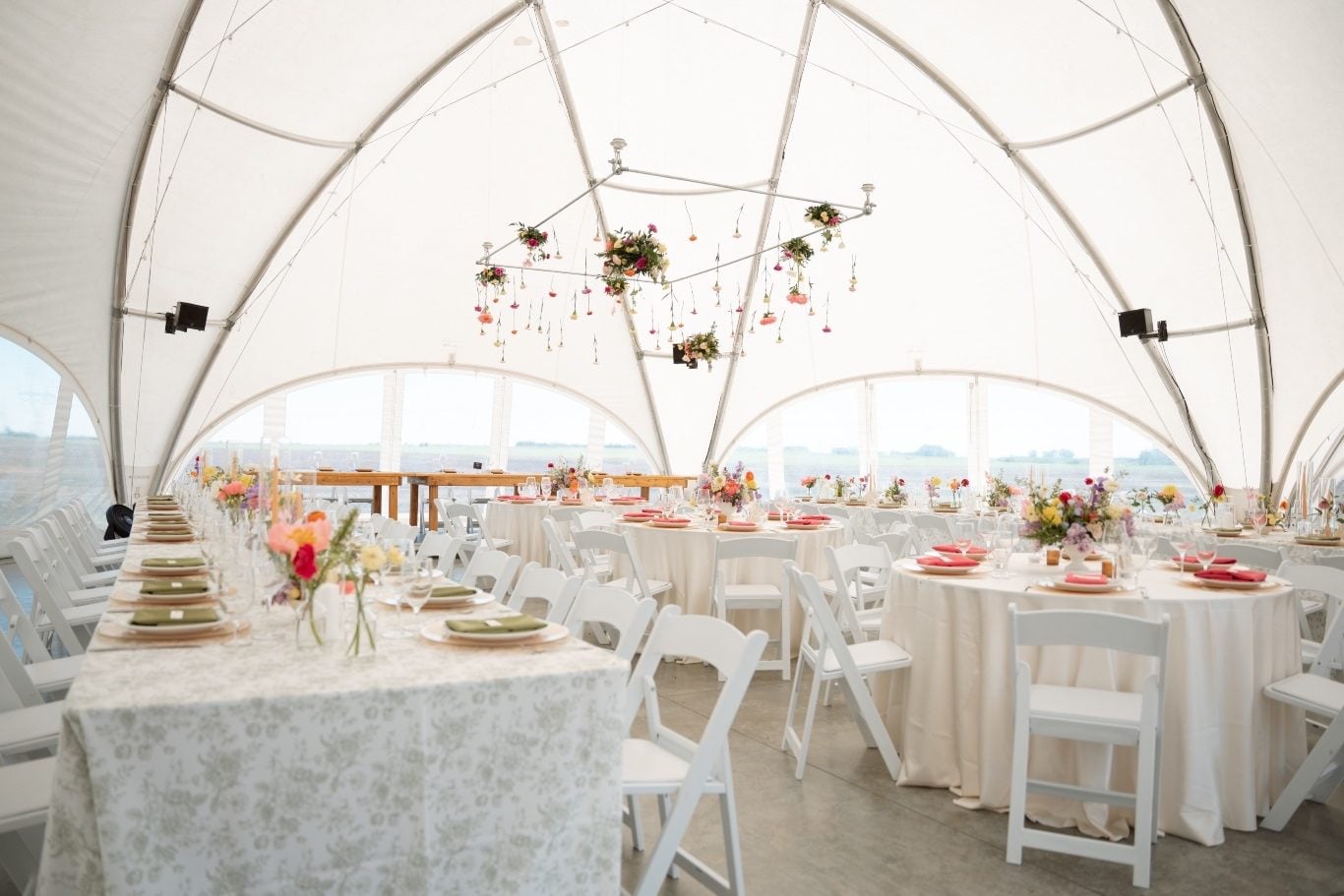 Colourful Tented Reception at River’s Edge The tented reception for this colourful wedding, featuring a hanging flower instillment, colourful centrepieces and garden inspired accents.