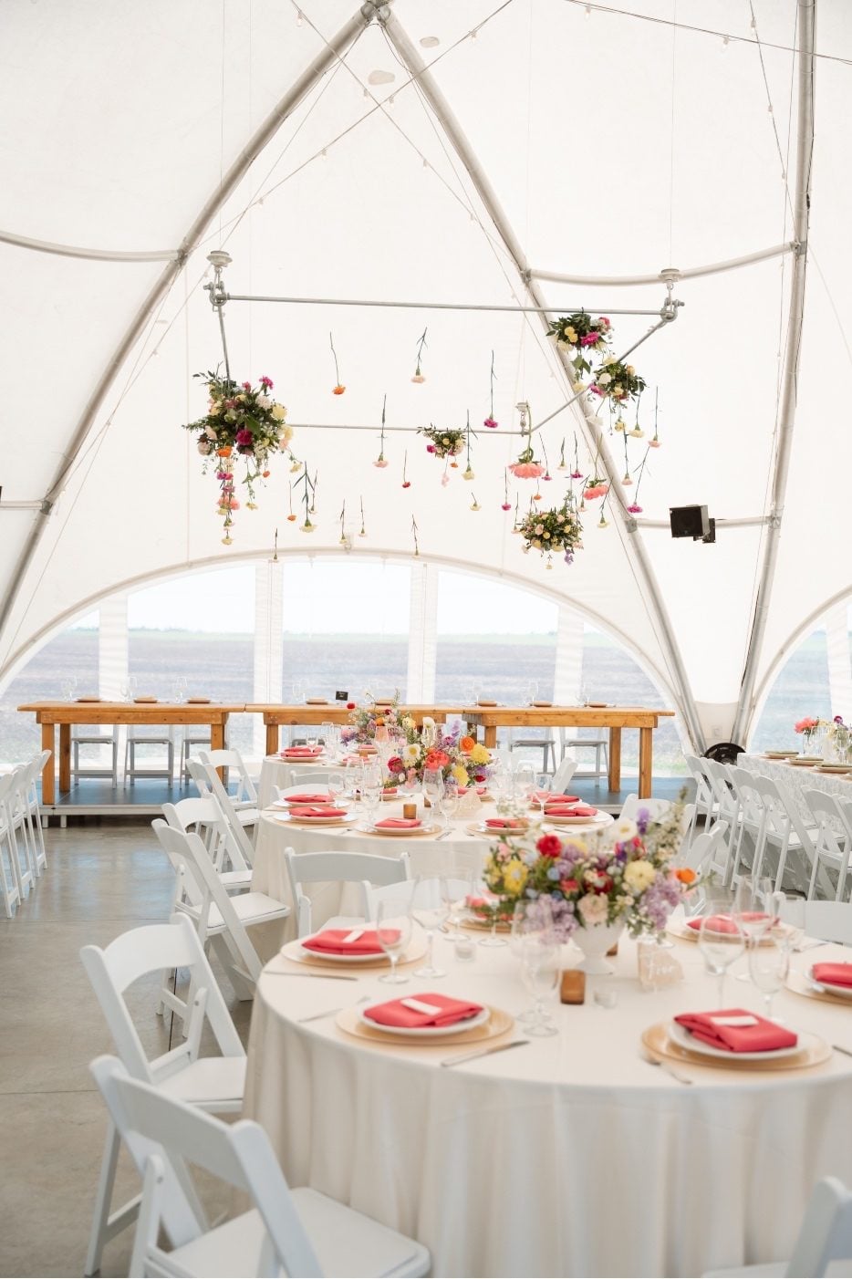 Colourful Wedding Reception Gorgeous reception set up for this colourful at River's Edge, showing the hanging flower installation over round guest tables with full, garden inspired centrepieces.