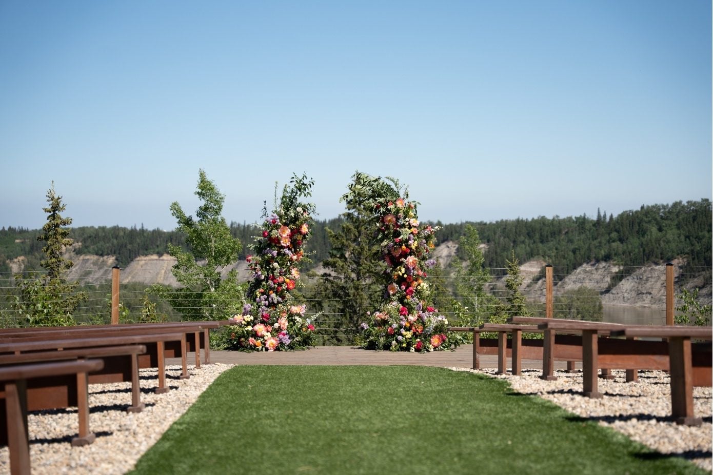 Colourful Wedding with Broken Arch The ceremony set up at River's Edge, looking down the aisle at the colourful broken arch.