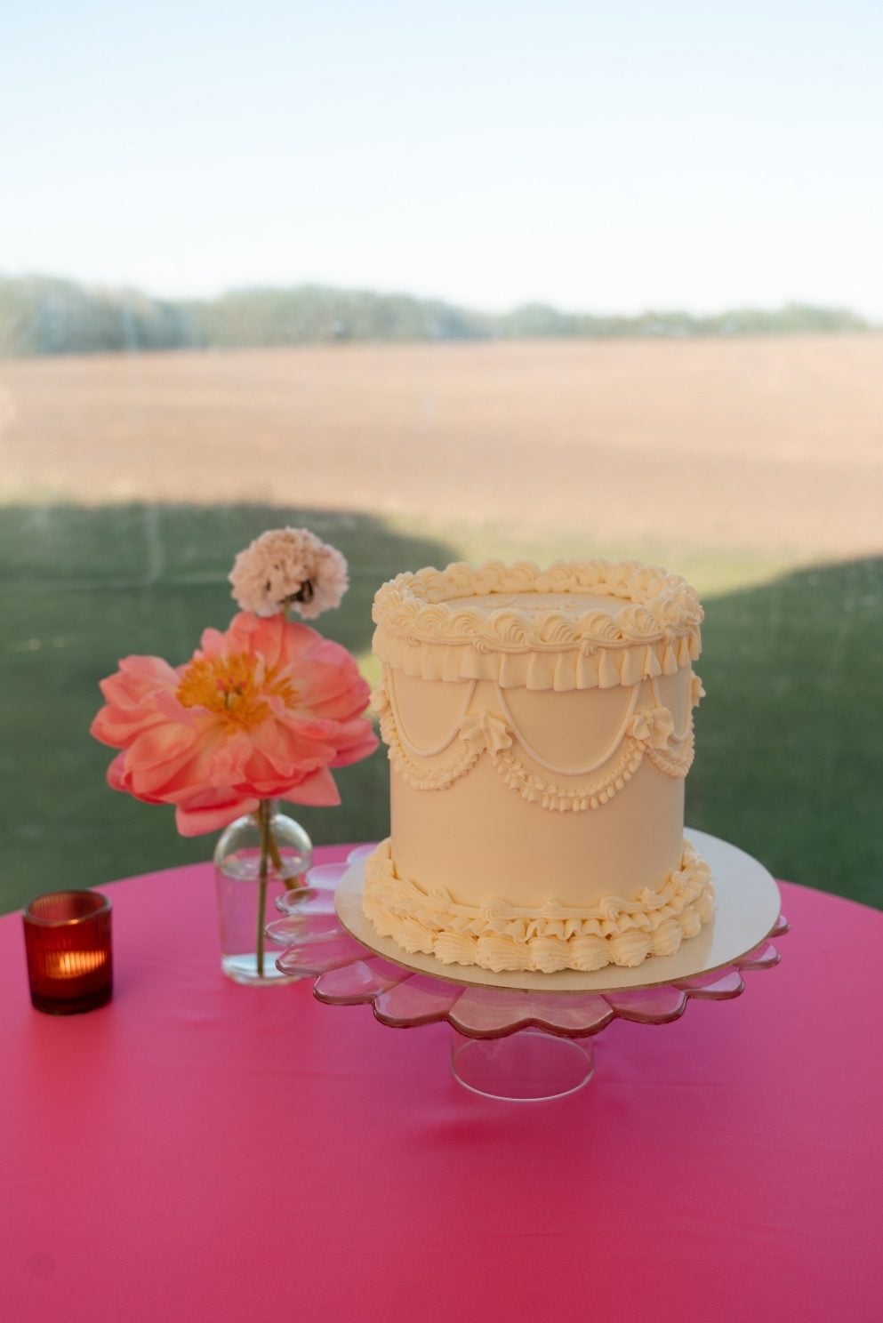 Coral Peony and Wedding Cake Simple, single tier wedding cake with buttercream frosting, next to a bud vase with a coral peony and scabiosa bloom.