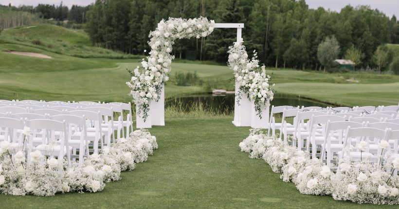 Wedding Ceremony Backdrops White wedding ceremony set up with floral arch accents, white floral arrangements on pillars as well as white arrangements going down the aisle.