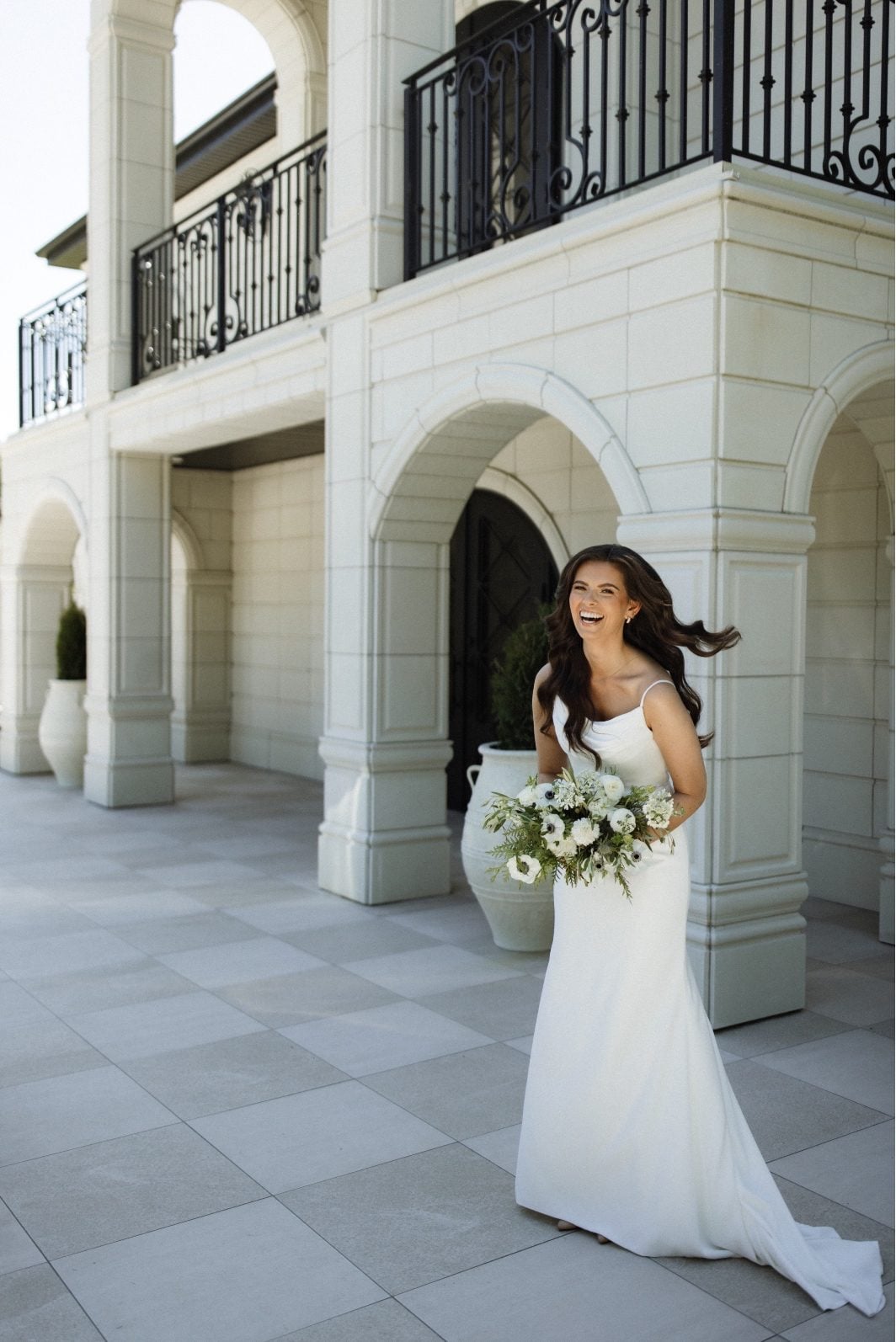 Bride at Archway Manor Bride laughing outside Archway Manor holding her white and green bridal bouquet,