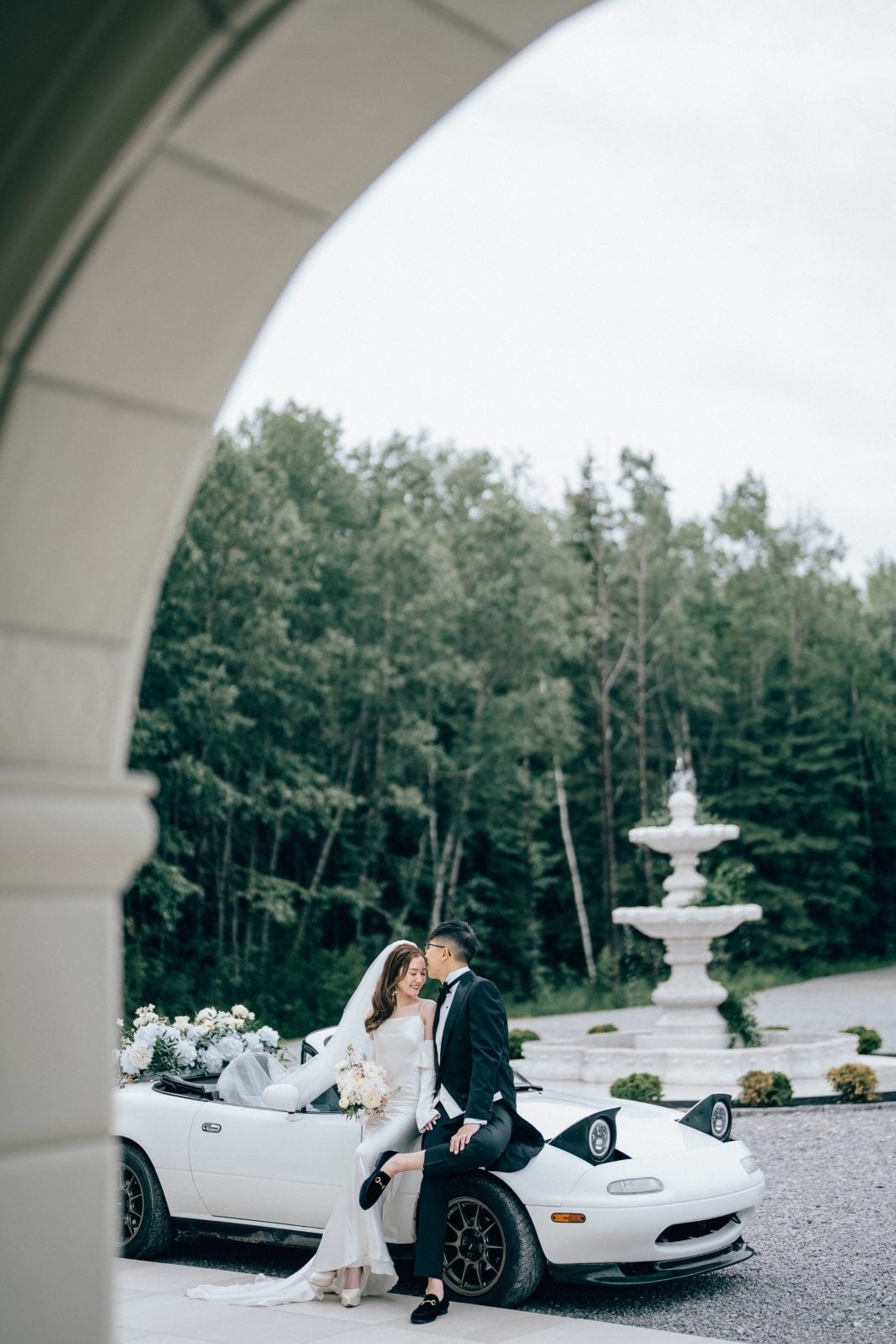 Bride and groom share a moment next to their white convertible car at this luxury wedding.
