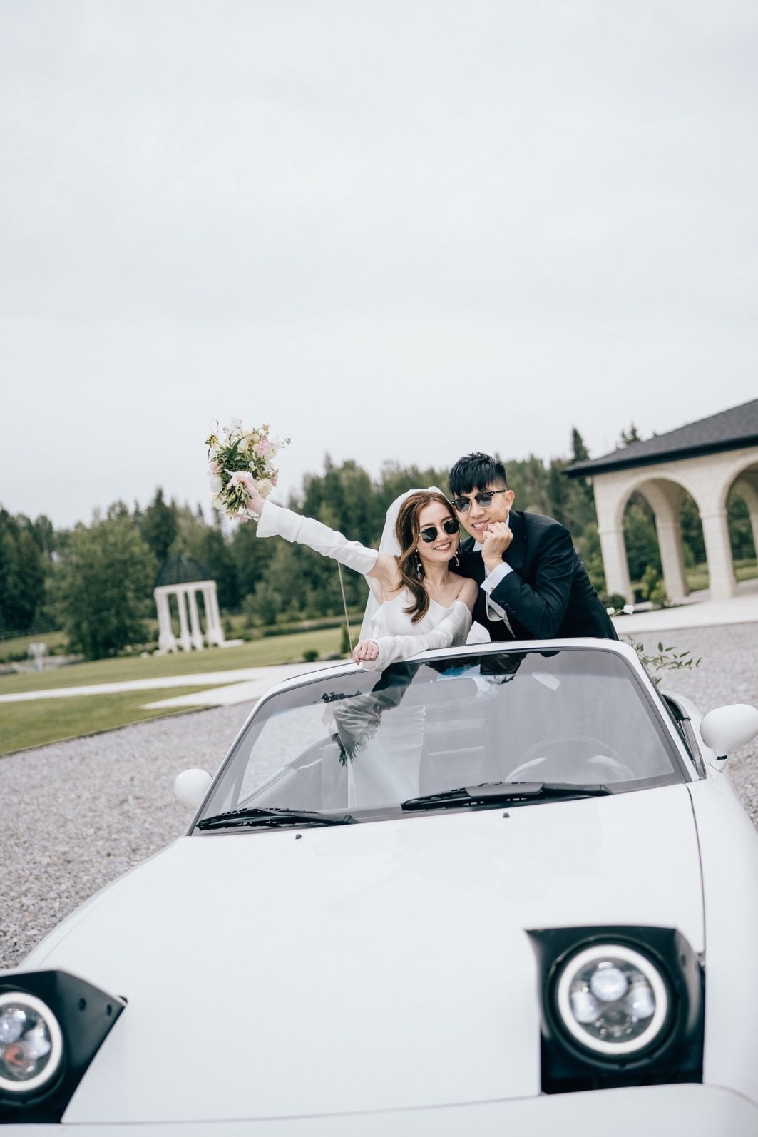 Bride and groom strike a pose for this luxury wedding in their white convertible.