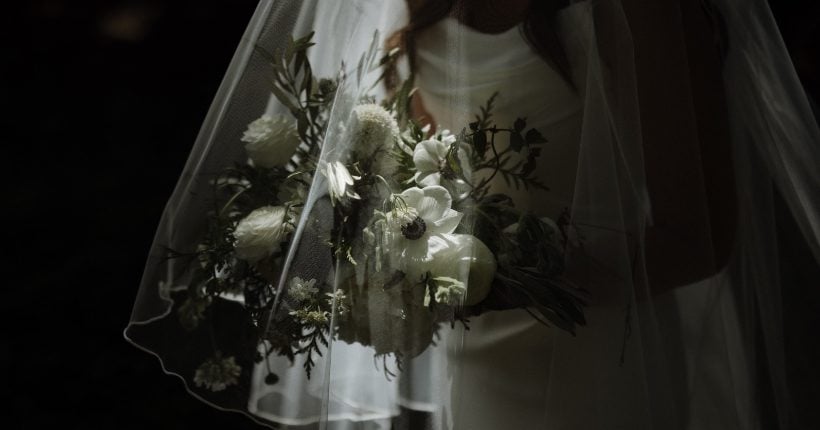 Veiled White + Green Bridal Bouquet FT A bride holding her white and green bridal bouquet under her veil