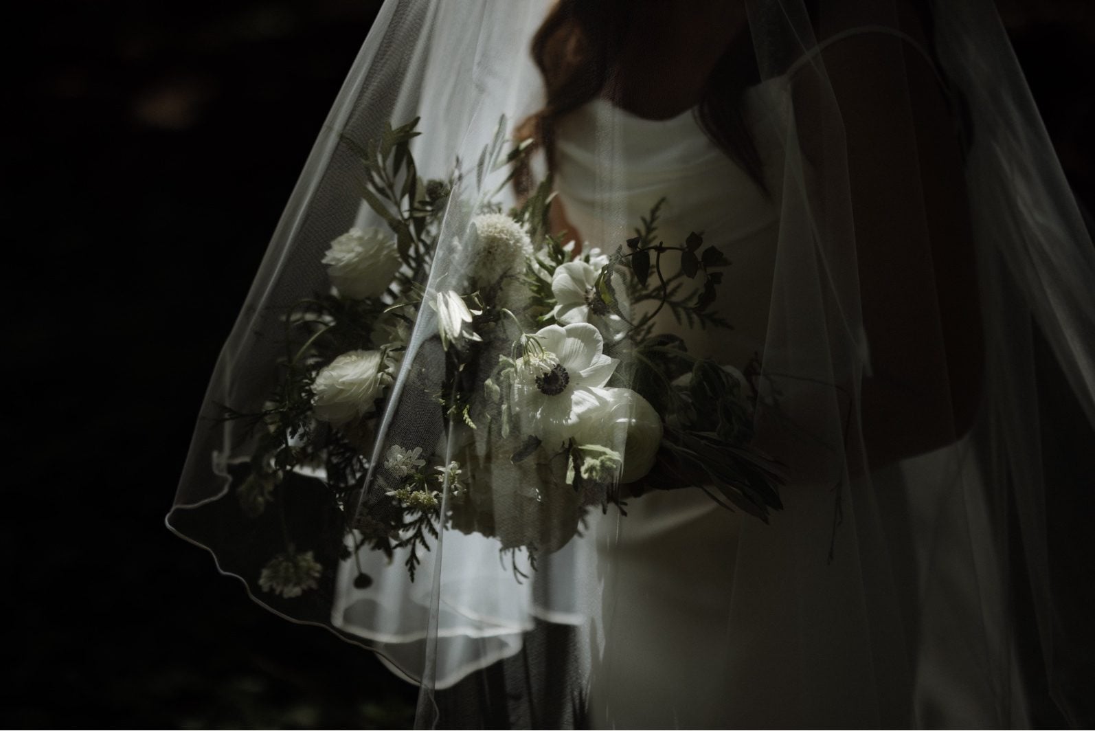 Veiled White + Green Bridal Bouquet A bride holding her white and green bridal bouquet under her veil