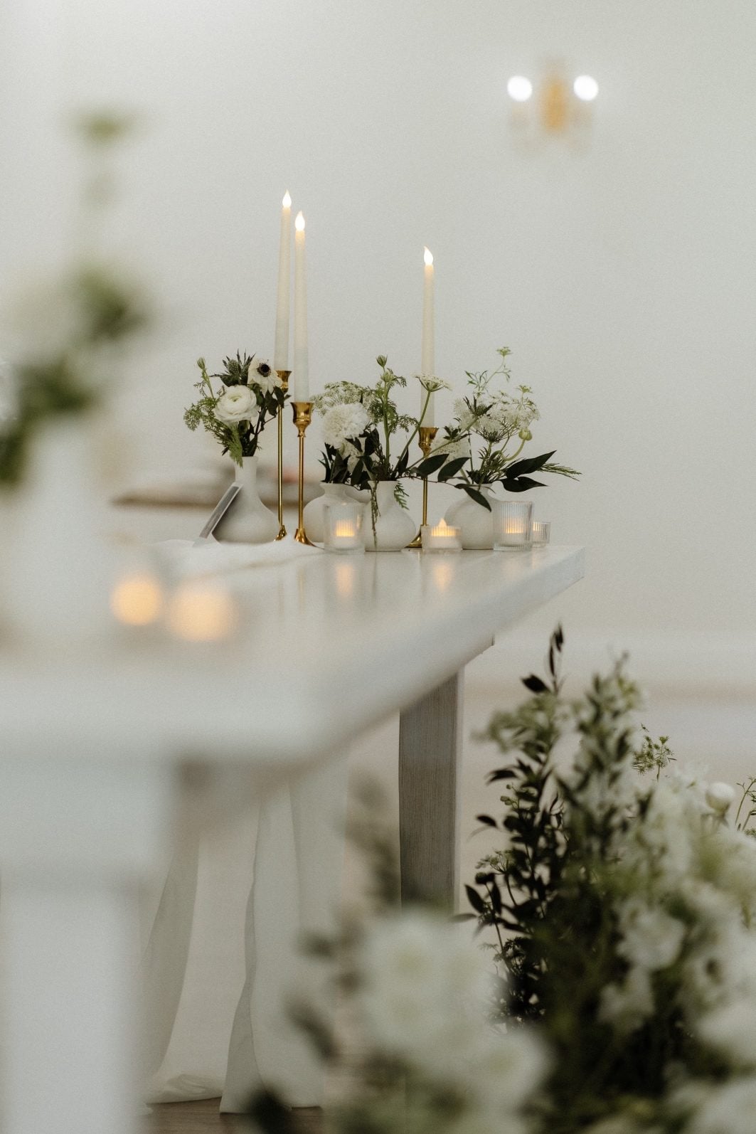 White + Green Reception Arrangements at Archway White and green sweetheart table with bud vases and taper candles with a large arrangement on the floor in front of the table,