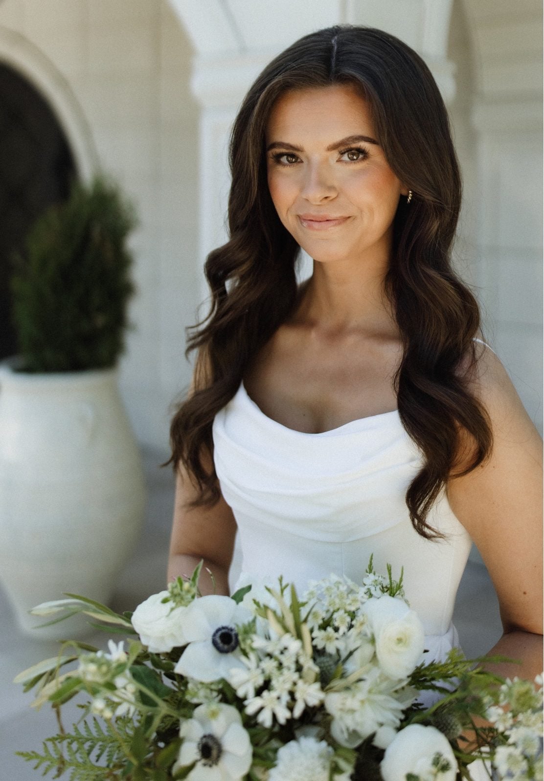 White and Green Bride at Archway Manor Our Calyx Bride smiles softly outside Archway manor holding a beautiful bridal bouquet in white and green garden inspired blooms including anemones, scabiosa ranunculus and lisianthus.