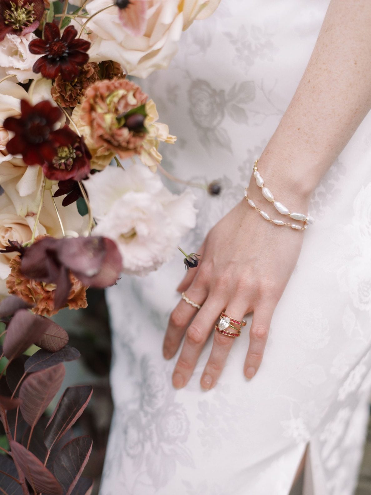 Justine Milton Marsala Rings Close up of cream, blush and burgundy bouquet with the bride's stunning rings and jewelry for the Marsala True to Hue Shoot by Bronte Bride.