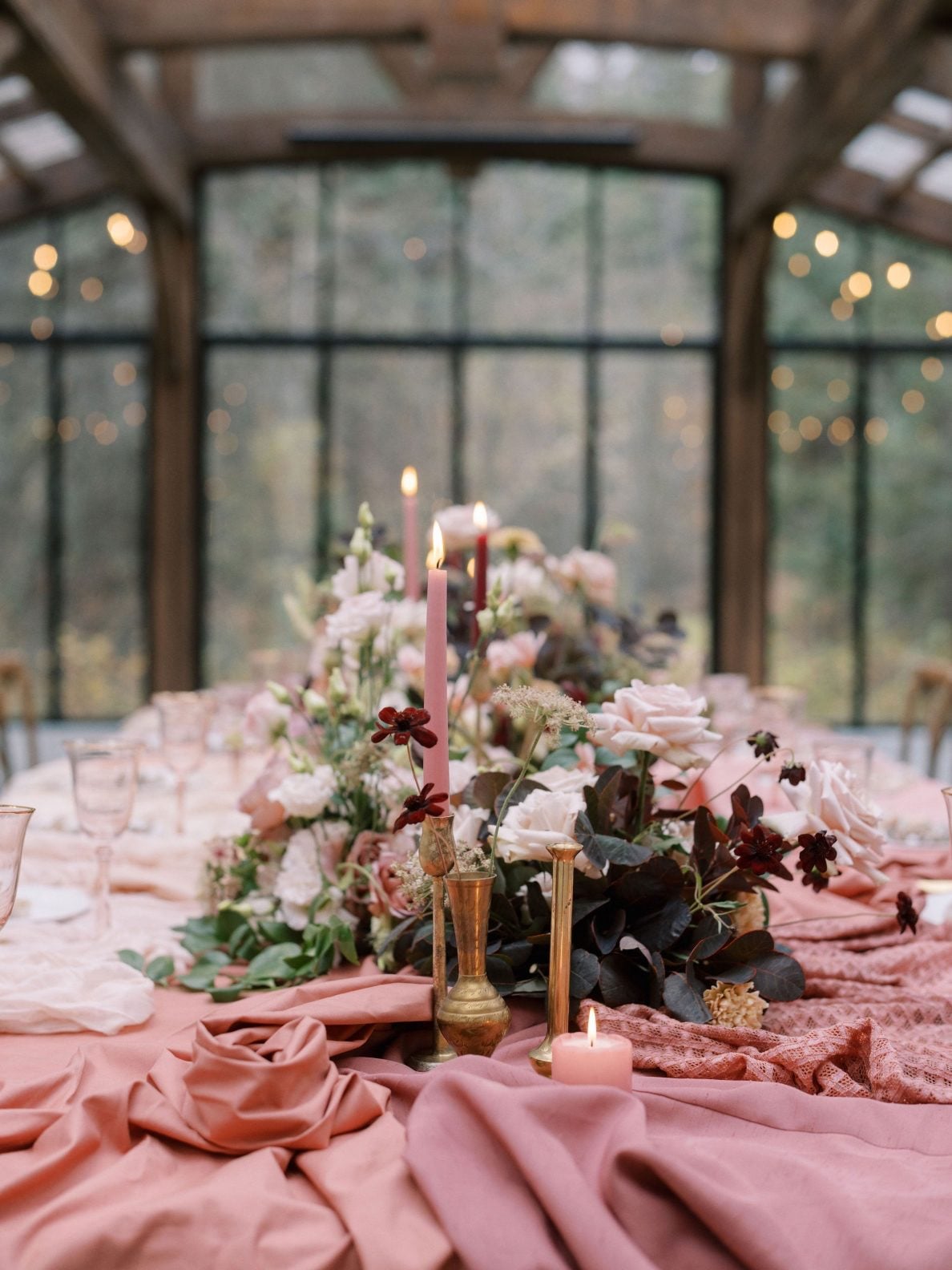 Justine Milton Marsala Tablescape True to Hue's photoshoot featuring marsala with free spirit vibes, pooling pink fabrics, flowers running down the centre of the table in beige, blush and burgundy accented with candles.