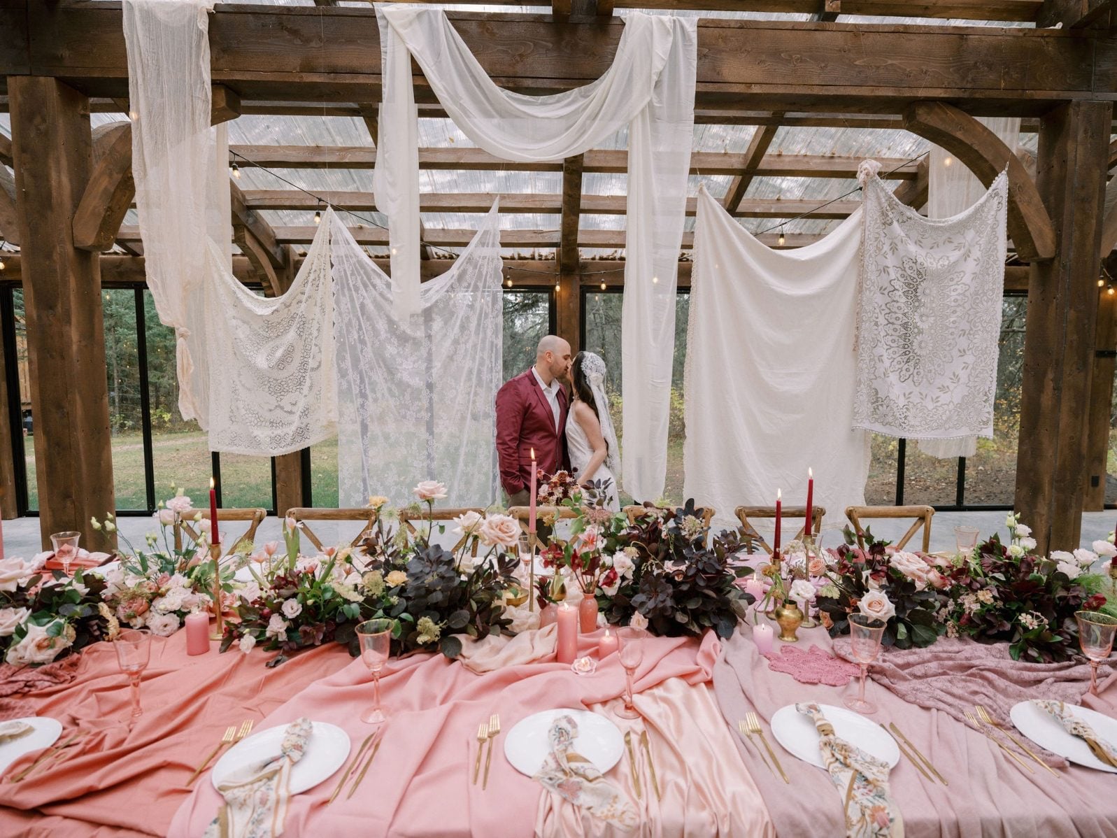 Justine Milton Marsala True to Hue Tablescape Behind stunning marsala table scape, couple shares a kiss amongst the draping lace suspended from the ceiling.