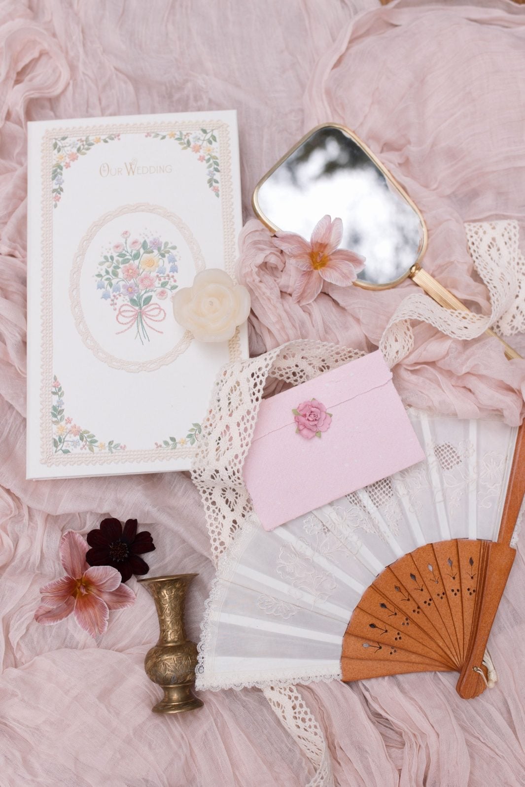 Nikki Collete True to Hue Marsala Flatlay A flatlay image for this Marsala True to Hue photoshoot by Bronte Bride featuring rings, stationery, lace, fan, blush, pink and burgundy blooms.