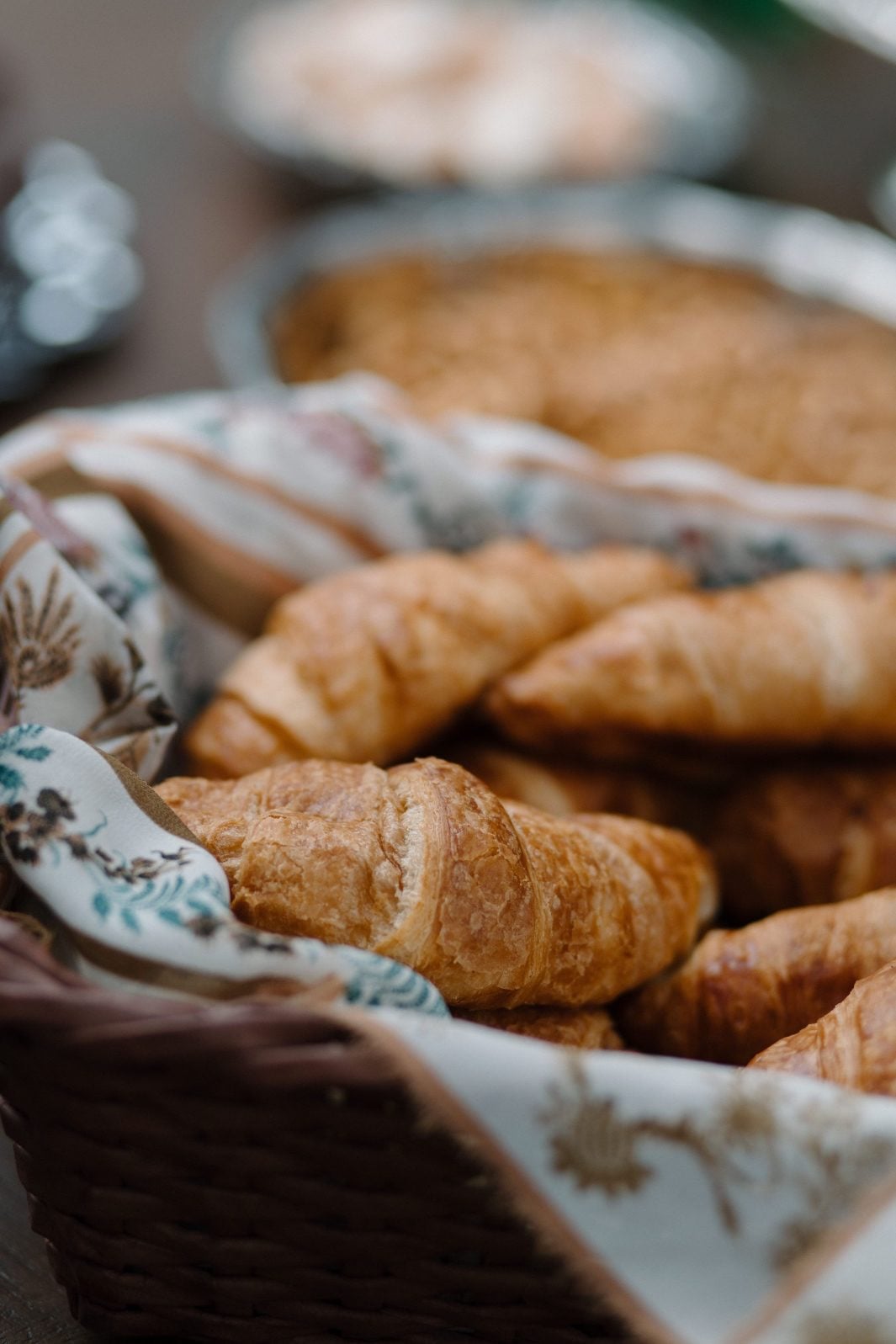 Nikki Collette True to Hue Croissants A basket lined with floral pattered linens holding croissants at this True to Hue photoshoot for Bronte Bride.