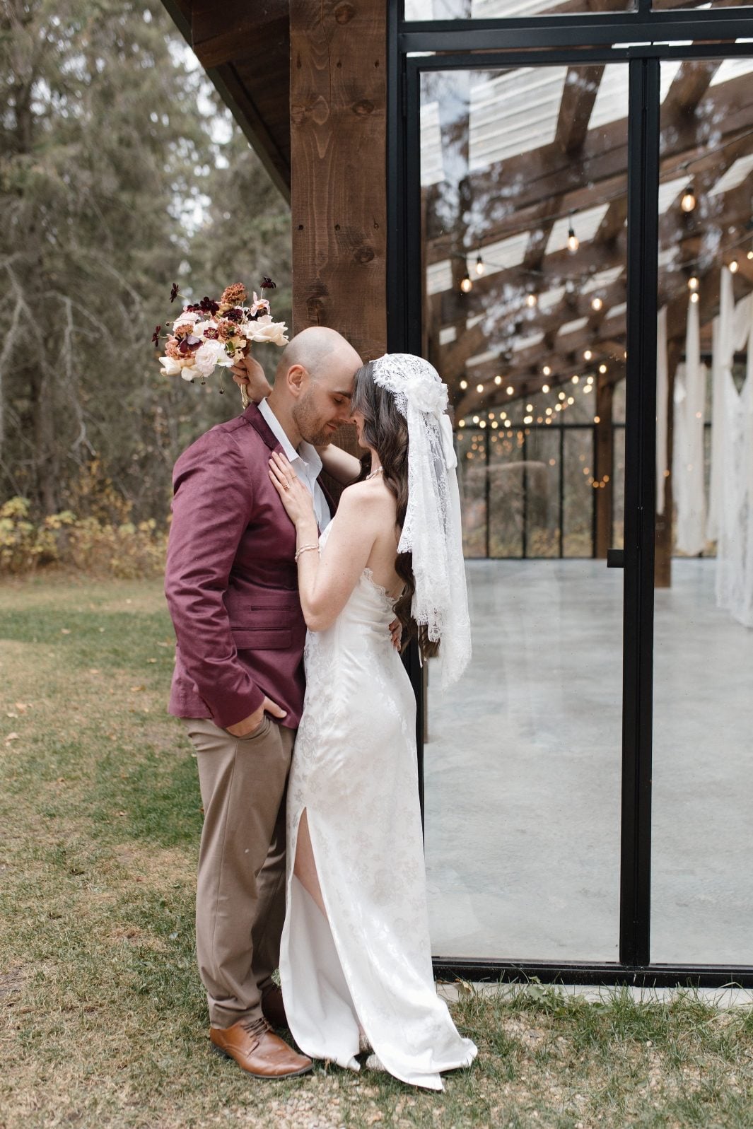 Nikki Collette True to Hue Marsala Couple at The Valley Couple leaning in close for a kiss at the beautiful glass reception space at The Valley Weddings.