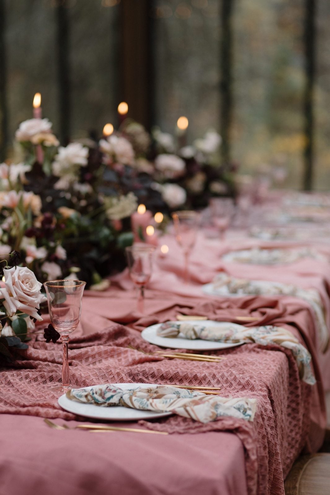 Nikki Collette True to Hue Marsala Table Gorgeous marsala inspired table scape with luxurious pink draped linens, abundant centrepiece running the length of the table in blush and burgundy lit warmly by candlelight.