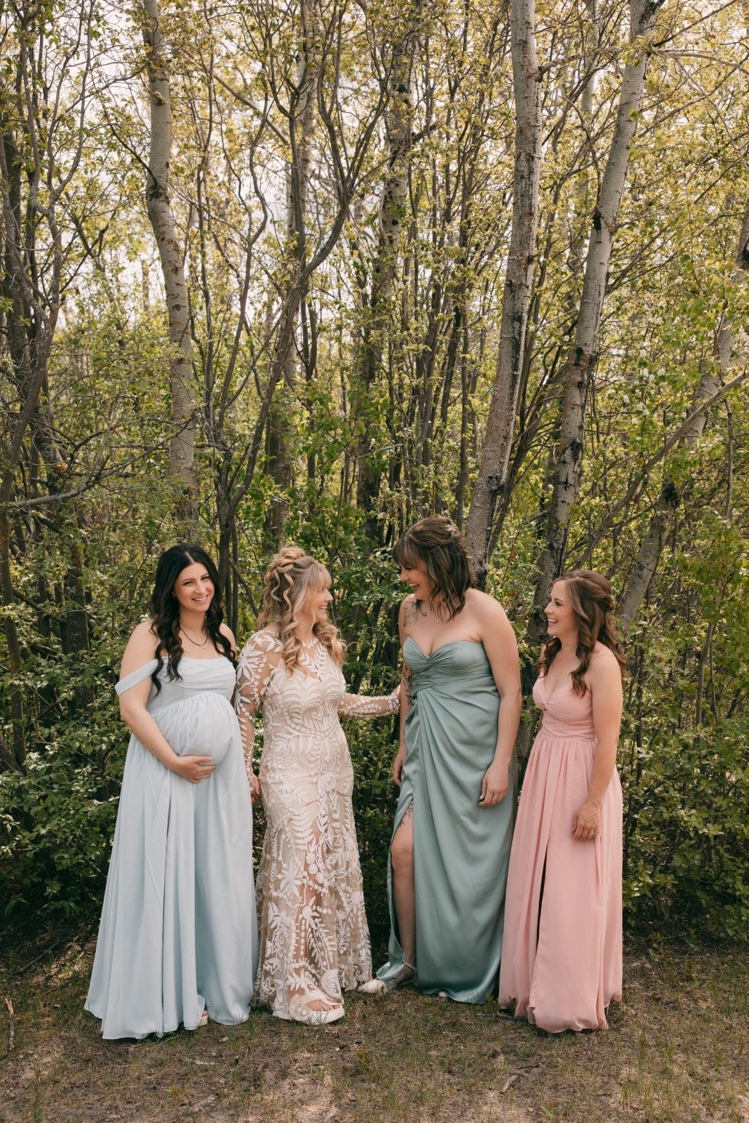 Bride with bridesmaids wearing soft blue, green and pink dresses at a colourful rainbow ombre wedding.