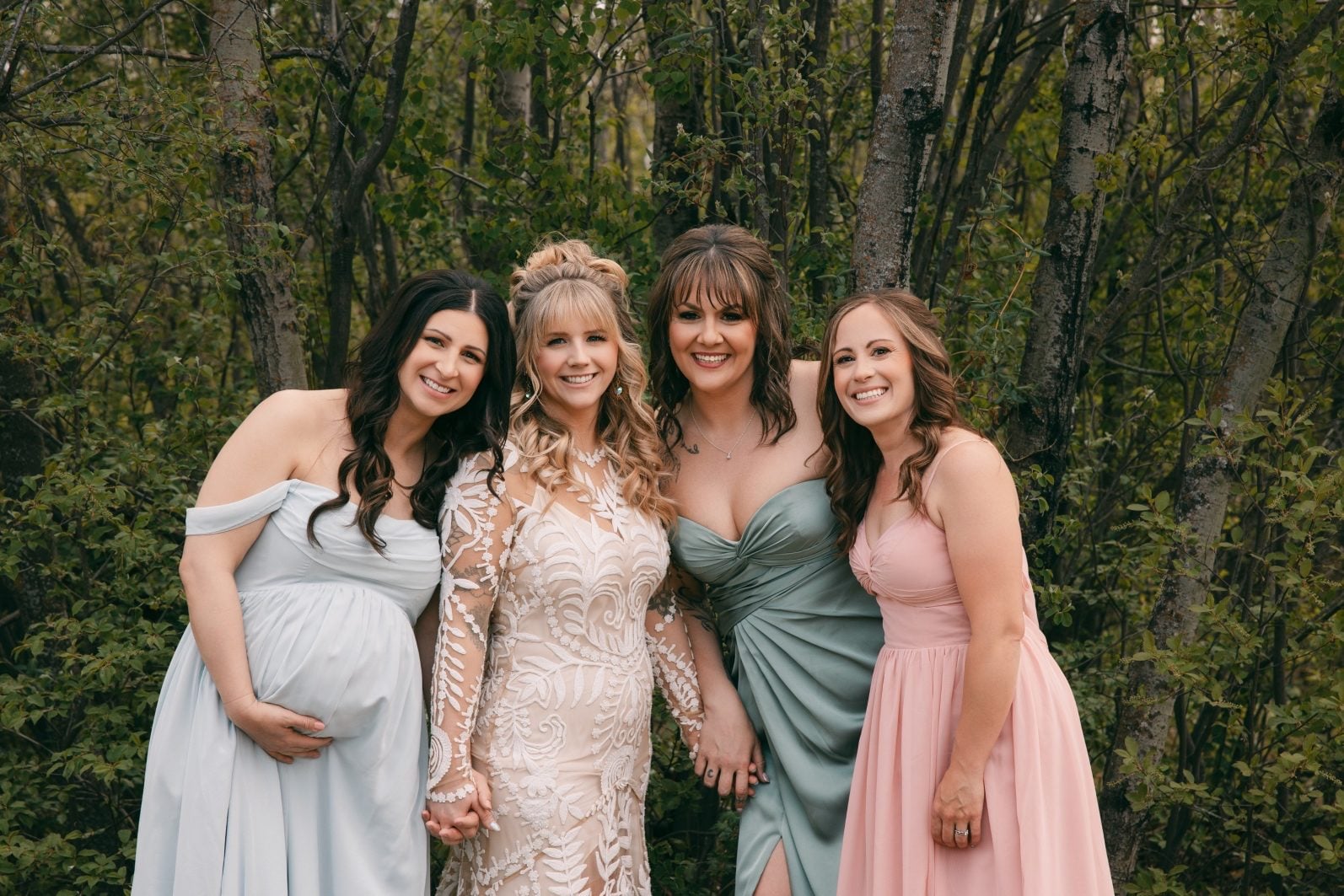 Bride smiling with bridesmaids at a colourful rainbow ombre wedding, bridal party wearing soft blue, green and pink dresses.
