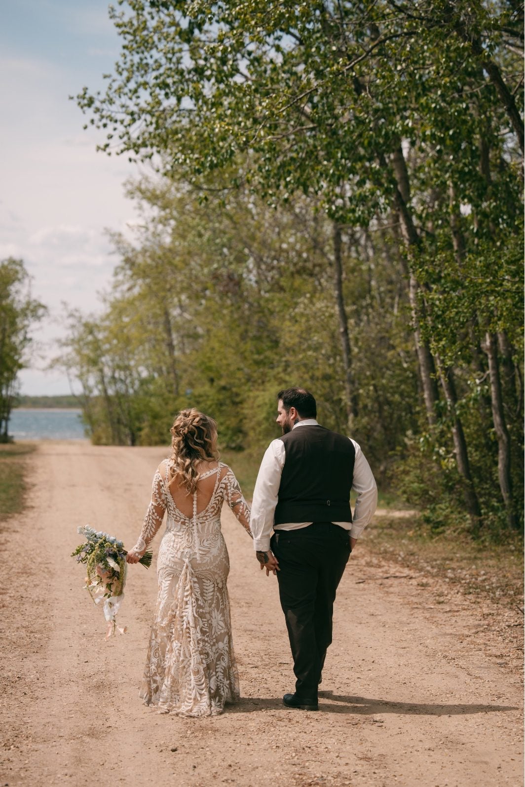 Bride and groom walking hand in hand on a path to Buffalo Lake.