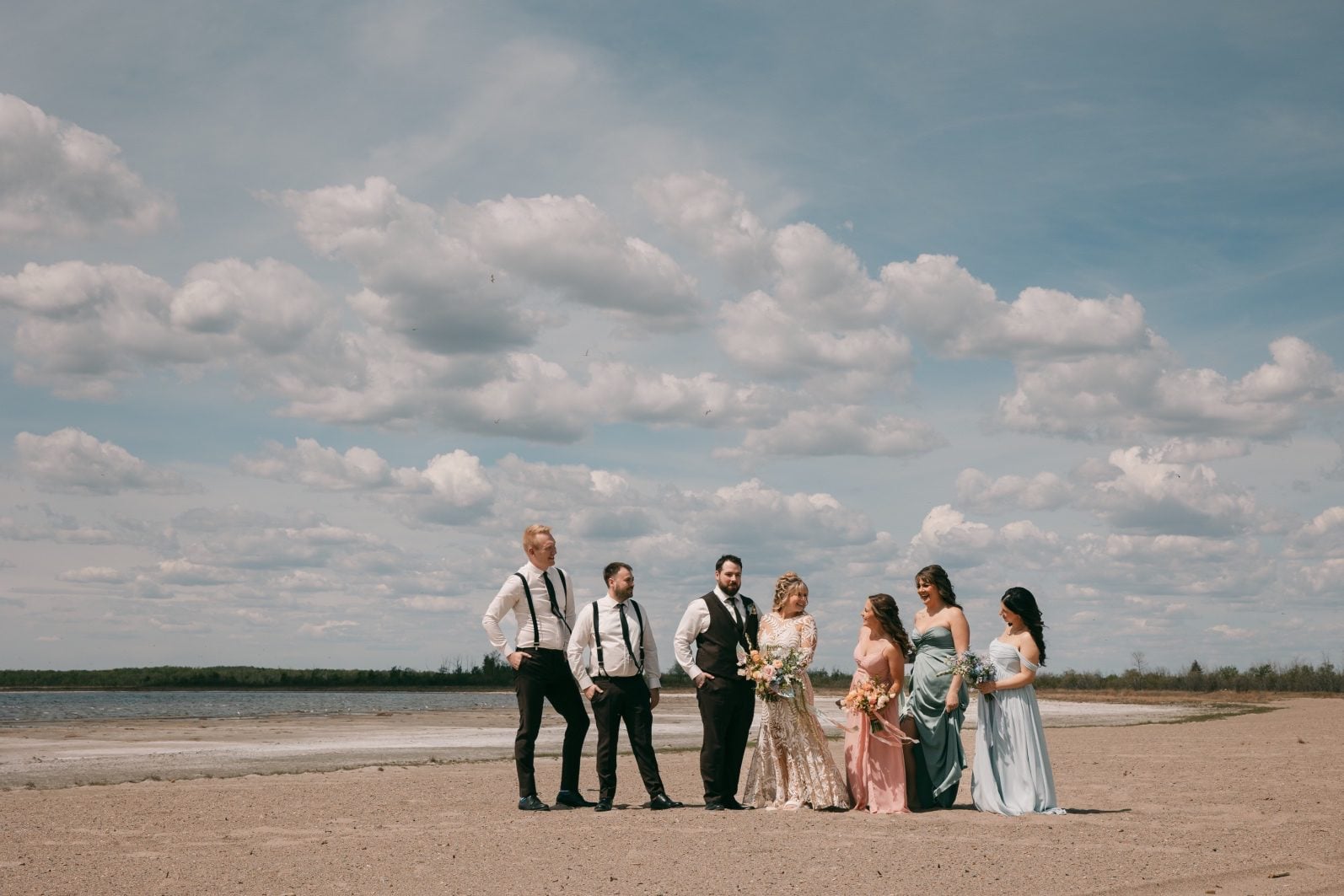 Wedding party beside Buffalo Lake in mismatched pastel dresses with colourful coordinated wedding bouquets.
