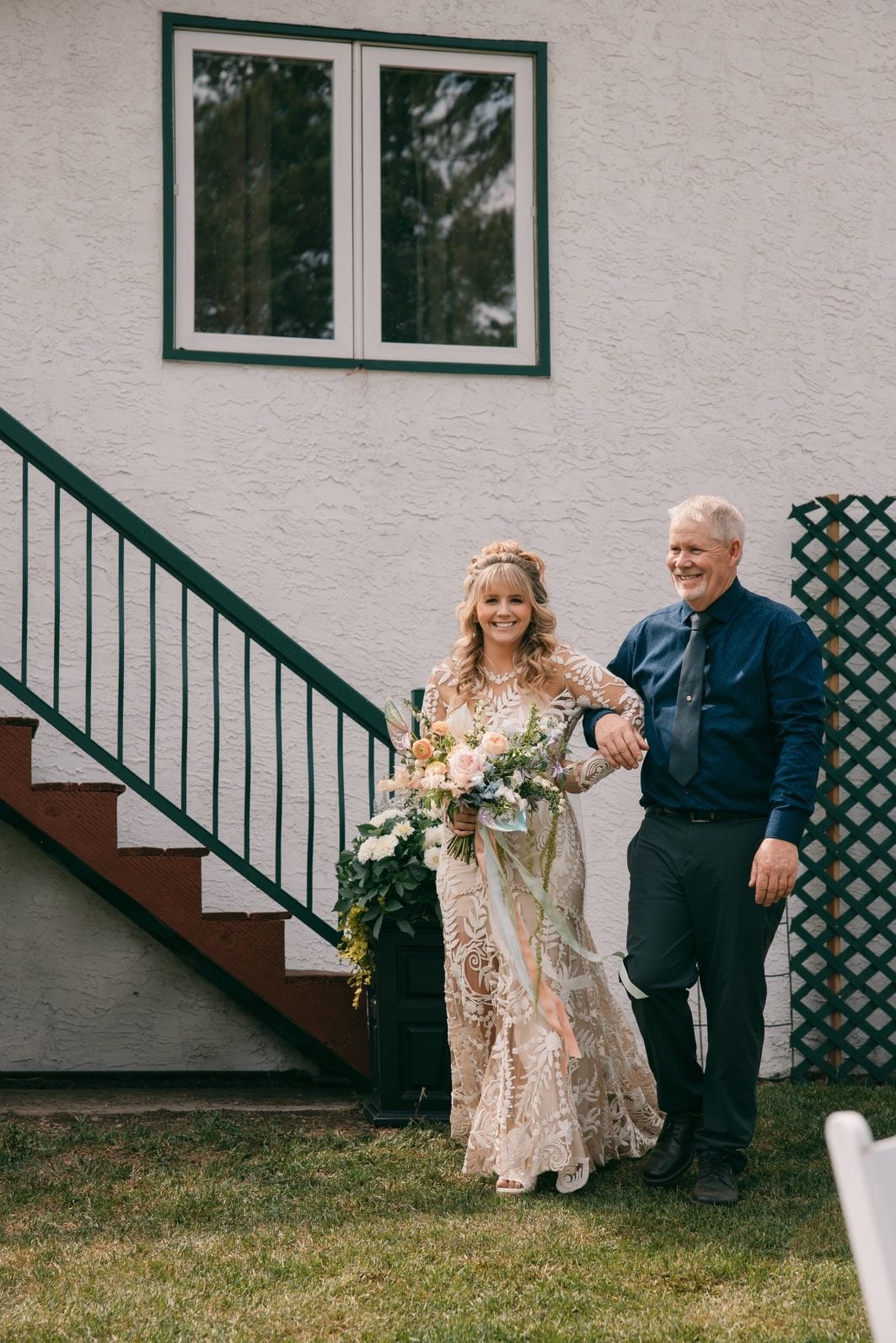 Bride walking into her outdoor wedding ceremony with her father, carrying a garden inspired pastel spring wedding bouquet.