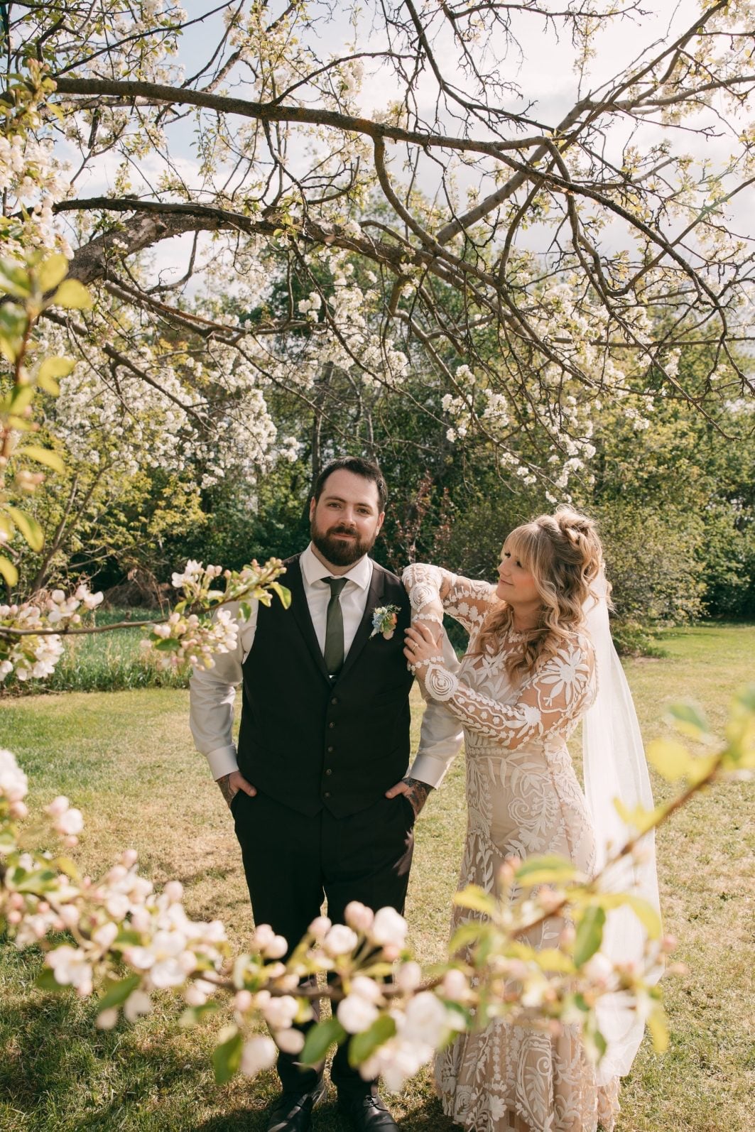 Bride and groom surrounded by flowering branches on the family property where their intimate rainbow ombre wedding took place.