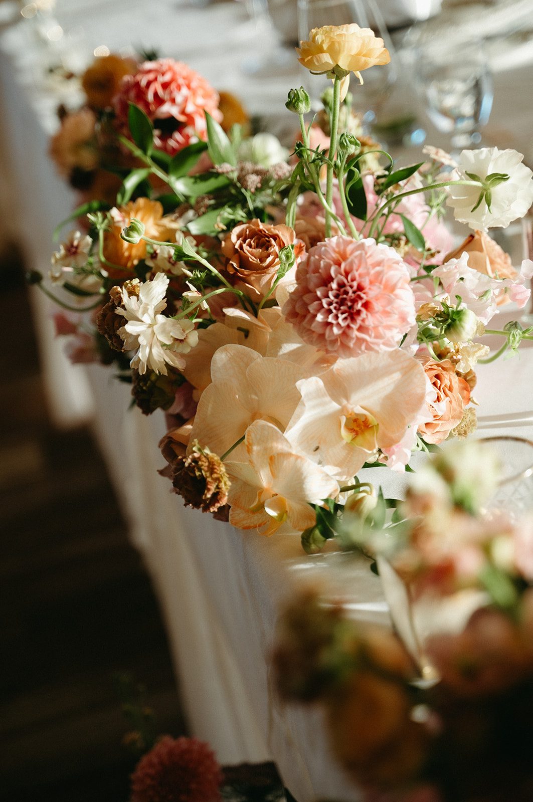 Close up of pink and peach head table arrangement, with the sun shining through its gardeny blooms.