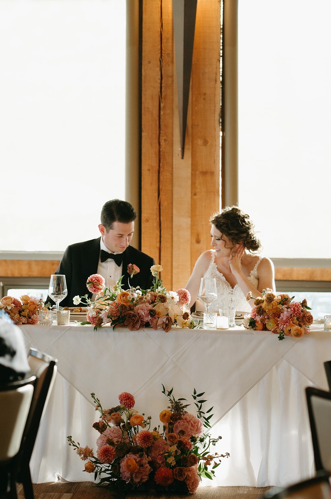 Bride and groom share a quiet moment at the head table during their reception.