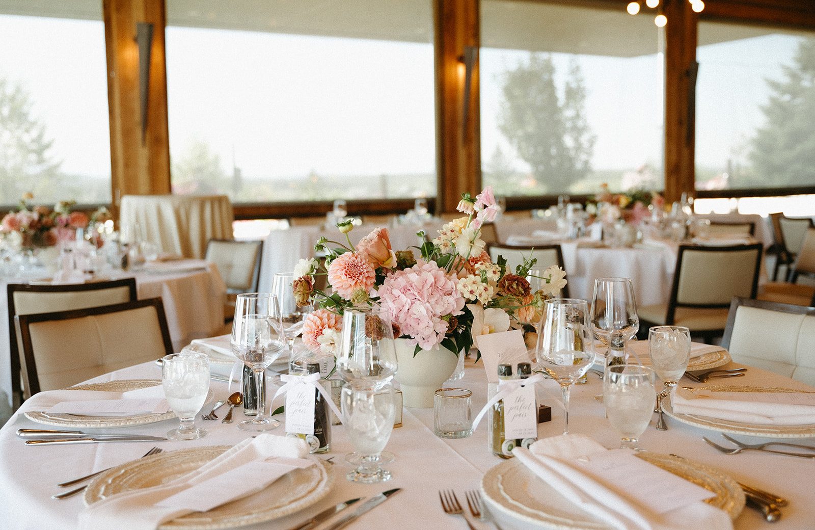 A guest table in the beautiful reception space at Pinebrook Golf & Country Club accented with a pink and peach floral centrepiece.