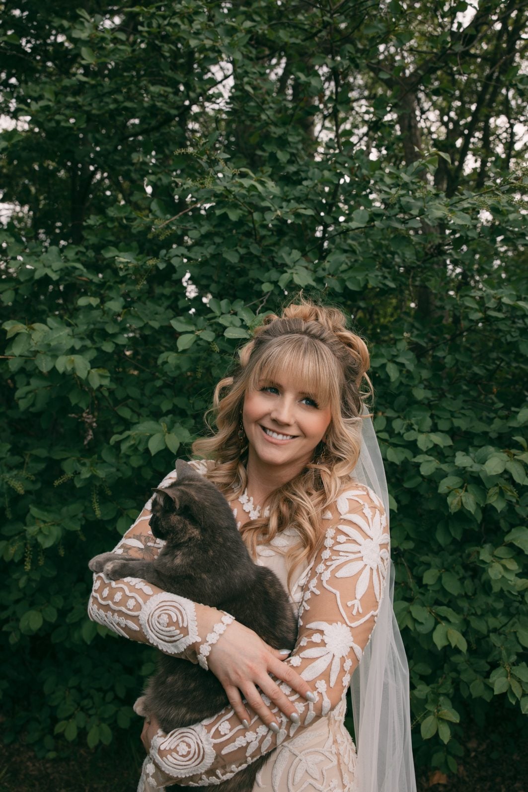 Calyx Floral Design staff member, Leigha, wearing stunning lace gown holding a cat.