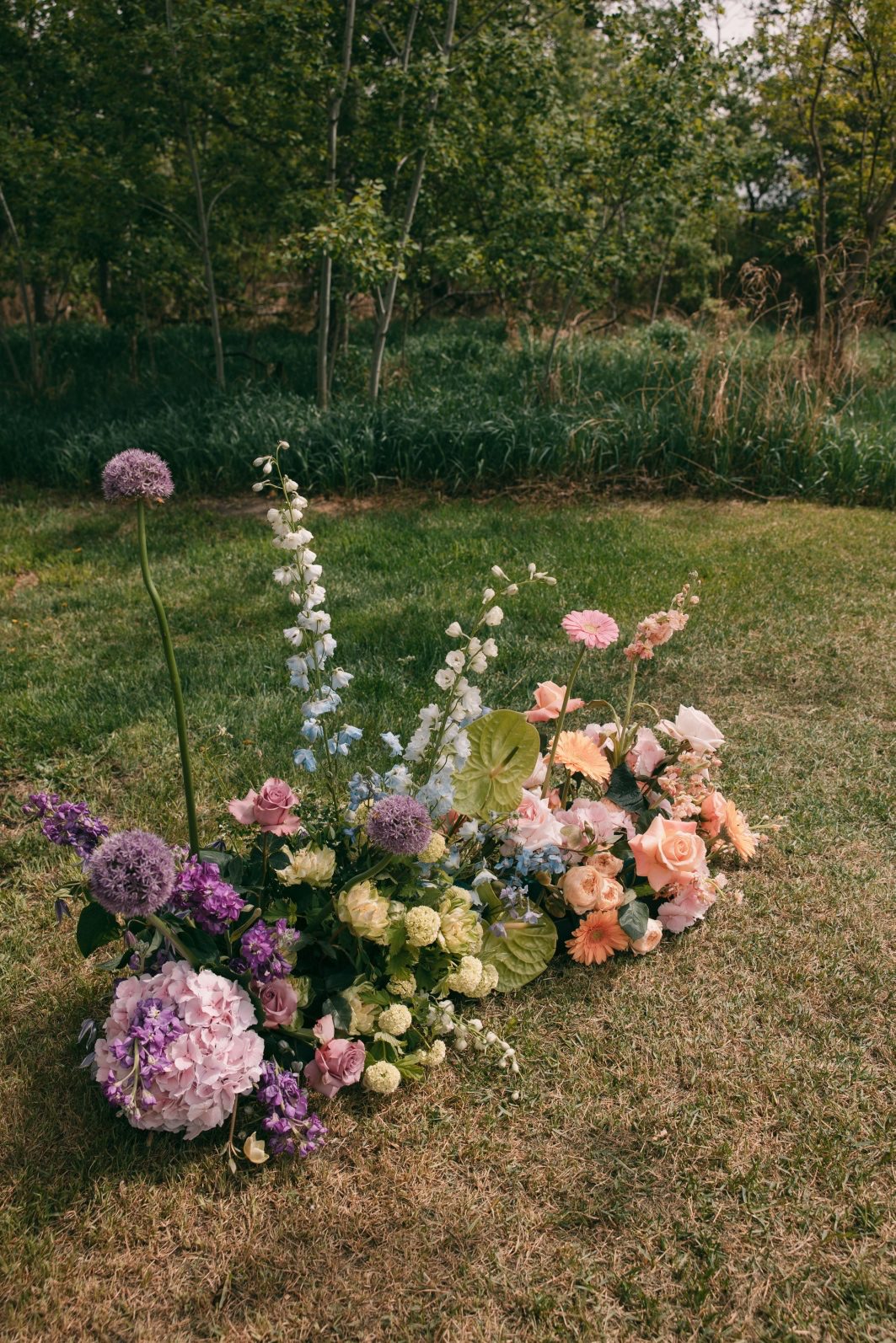 Colour blocked ceremony flowers with pink hydrangea, purple allium, delphinium, roses, anthurium and spring greenery.