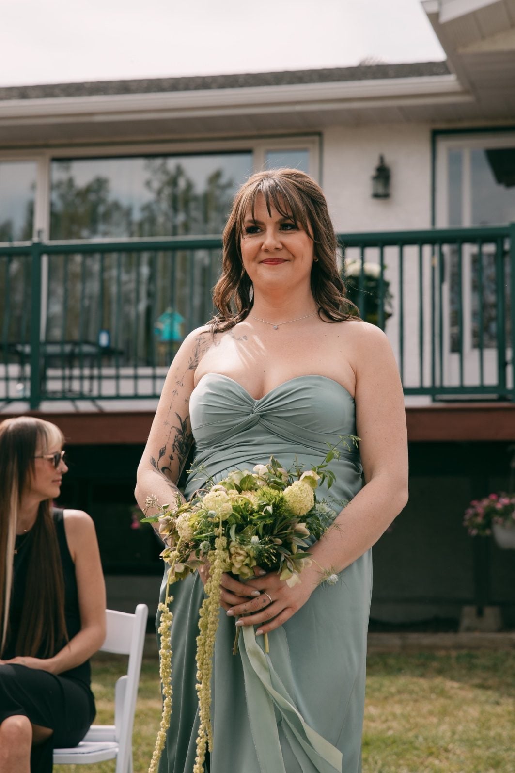Bridesmaid in a soft sage green dress carrying a textural green bouquet with trailing green amaranthus.