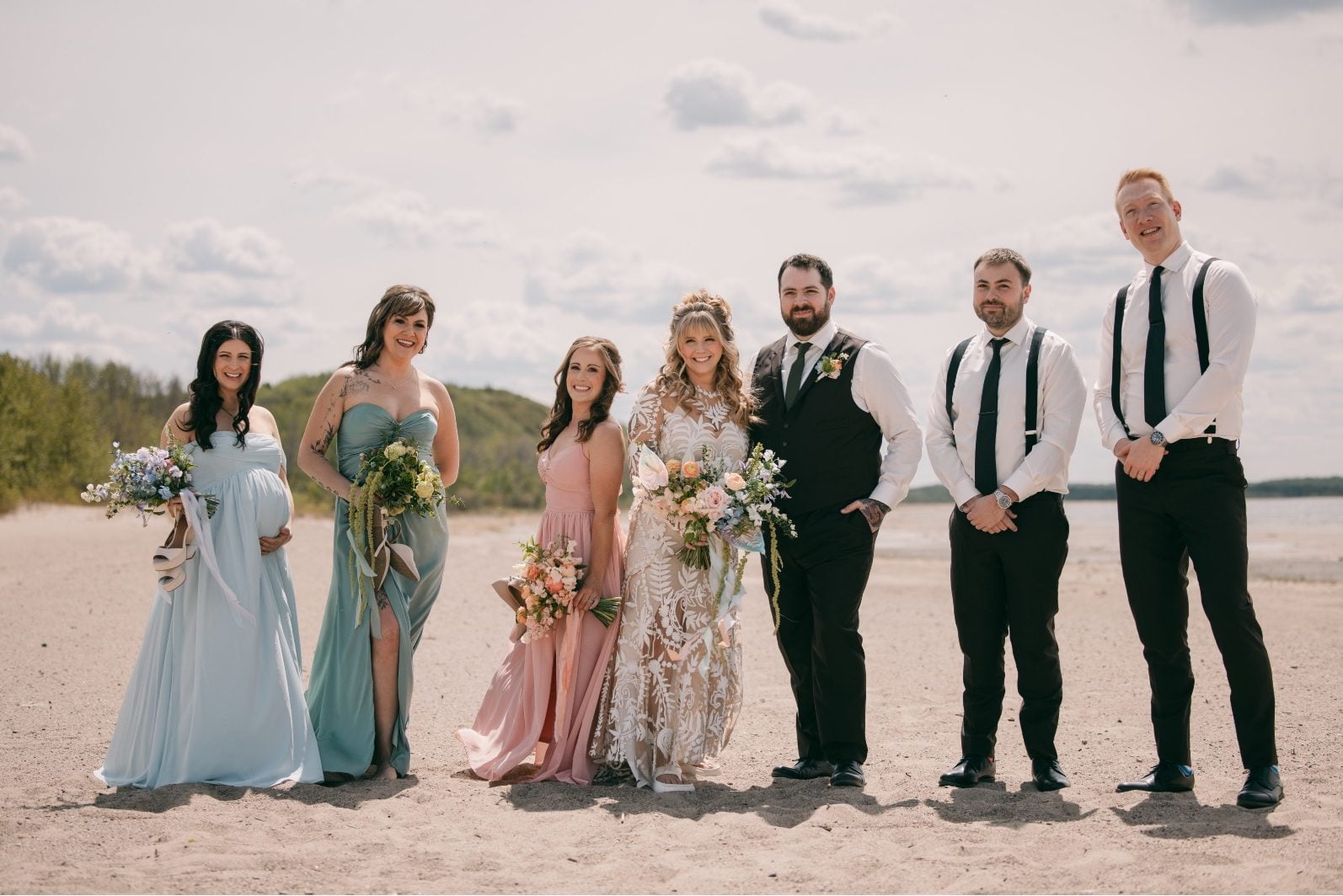 Wedding party in soft blue, green and pink with colourful rainbow ombre wedding flowers posing on the beach at Buffalo Lake.