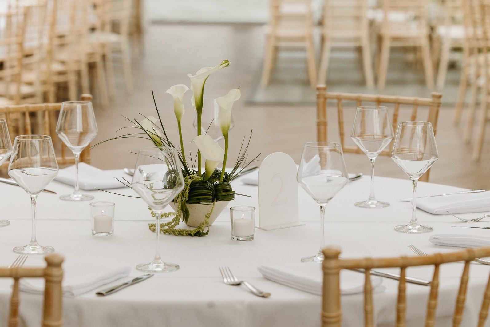 White + Green Structural Centrepiece White and green wedding flowers ikebana styled centrepiece with calla lilies, bear grass loops and amaranths.
