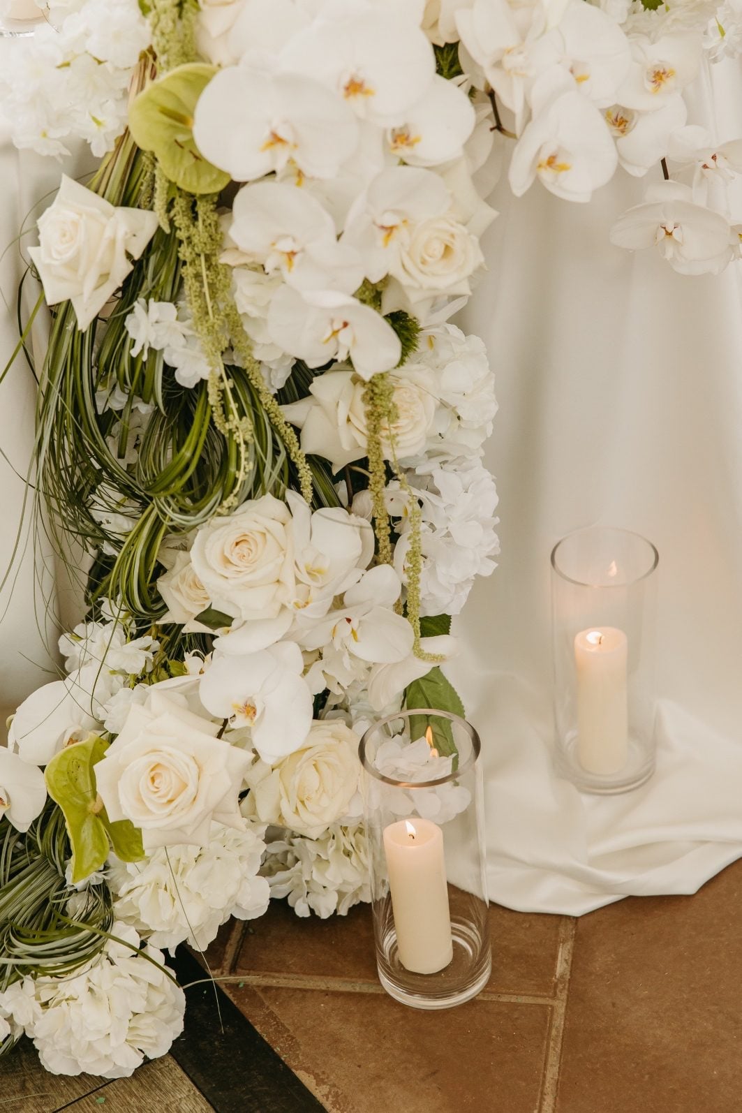 White + Green Wedding Flowers Close Up Close up of the stunning white and green wedding flowers cascading over the side of the sweetheart table - featuring hydrangea, roses, orchids, anthurium, amaranths and sculptural grasses.
