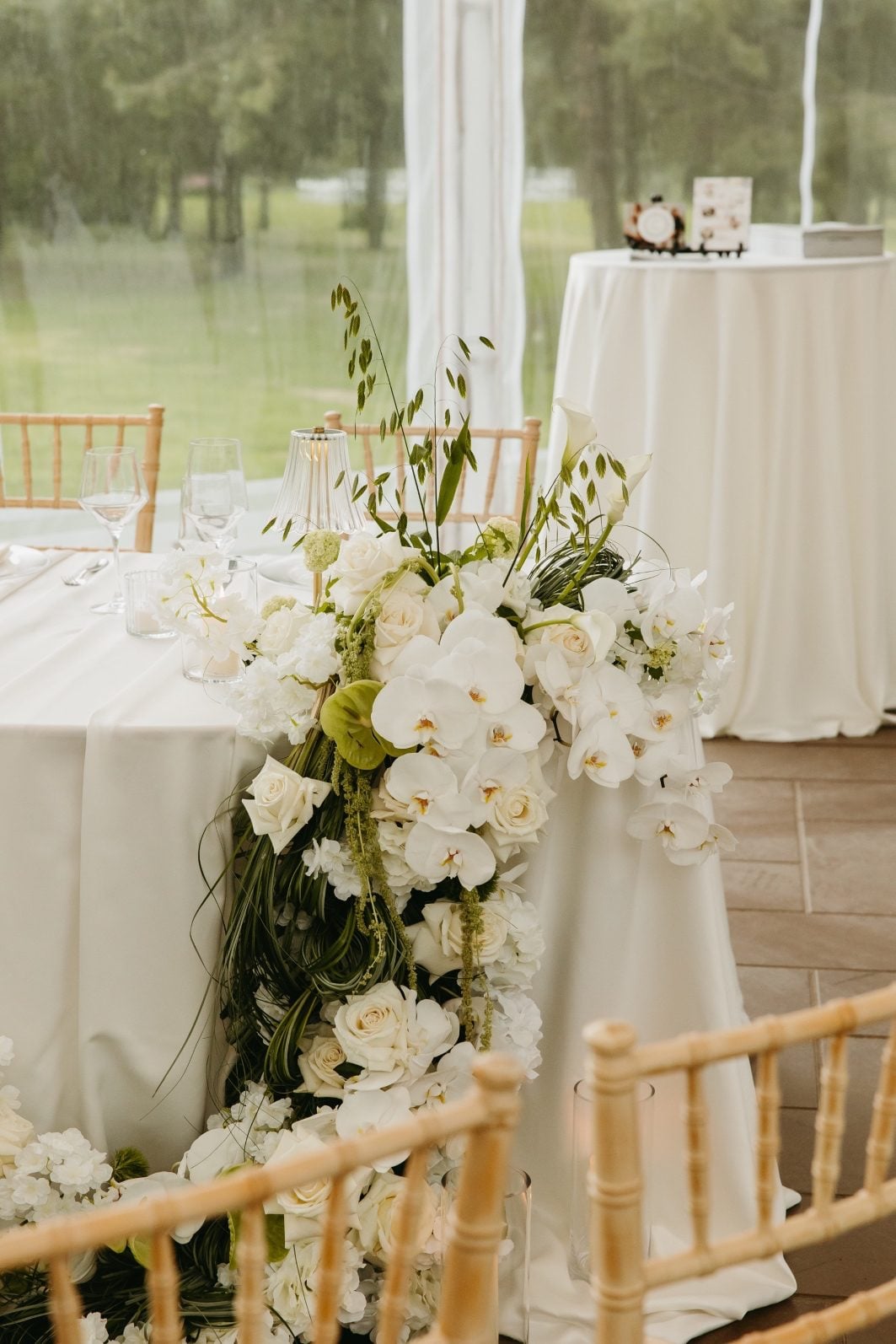 White + Green Wedding Flowers Sweetheart Table Sculptural floral waterfall cascading over the side of a table featuring white and green wedding flowers.