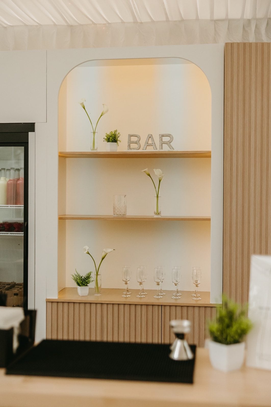 White and Green Wedding Flowers Bar Budvases Hilltops newly renovated bar space including blonde wood accents and shelves, featuring a few bud vases of calla lilies.