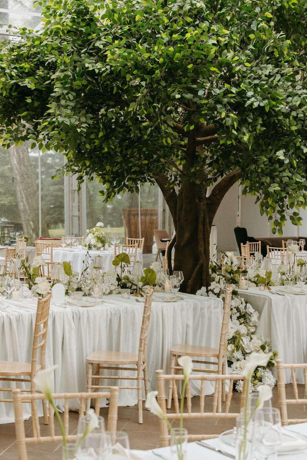 White and Green Wedding Flowers Reception Space The feature table from the side, showing that along with the abundant floral waterfall cascading from the front, two more extend out from the middle to either side for an elaborate floral display.