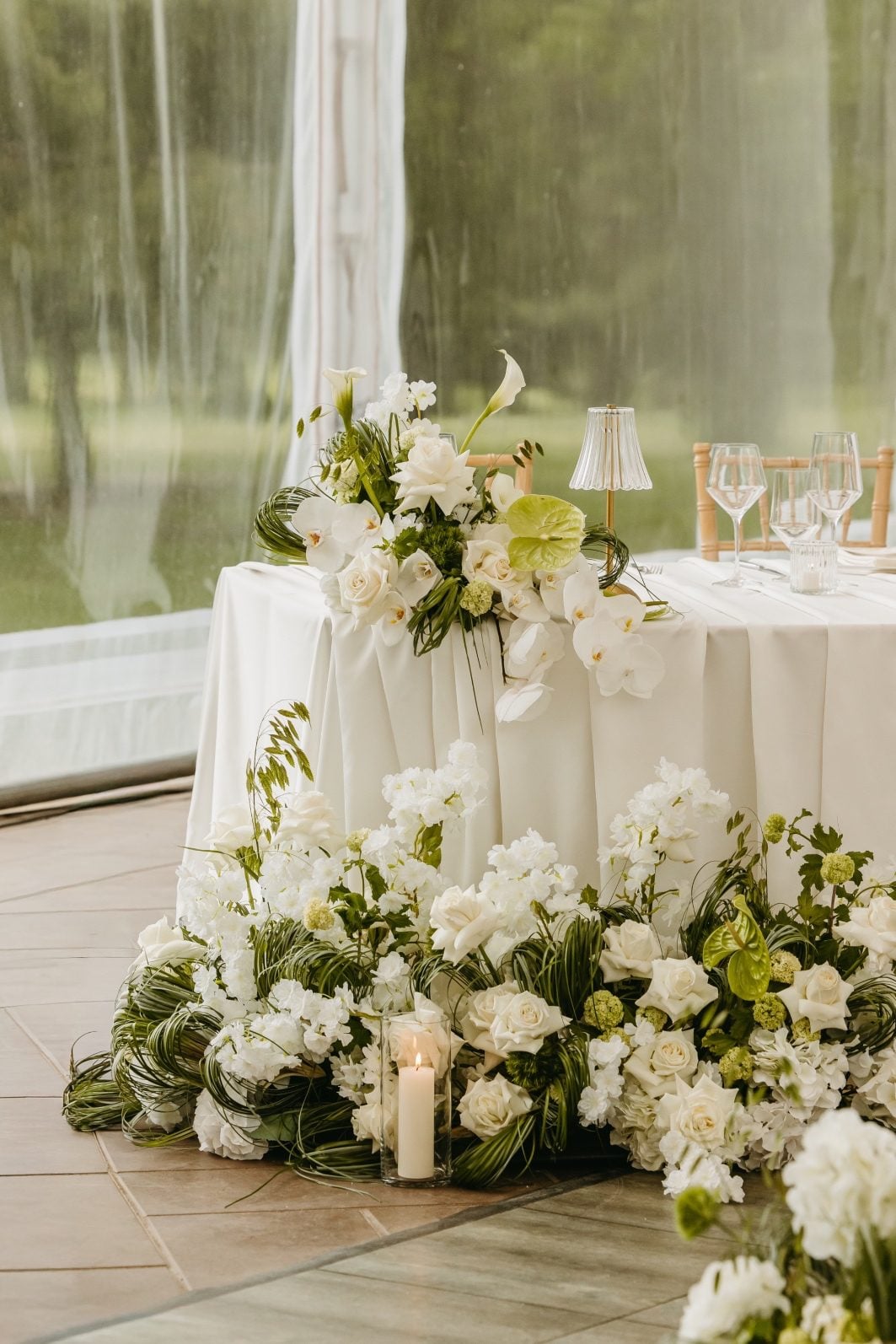 White and Green Wedding Flowers Sweetheart Table Stunning sweetheart table with a bouquet on one corner, a gorgeous floral waterfall on the other, as well as a large, stunning arrangement on the floor in front of the table.