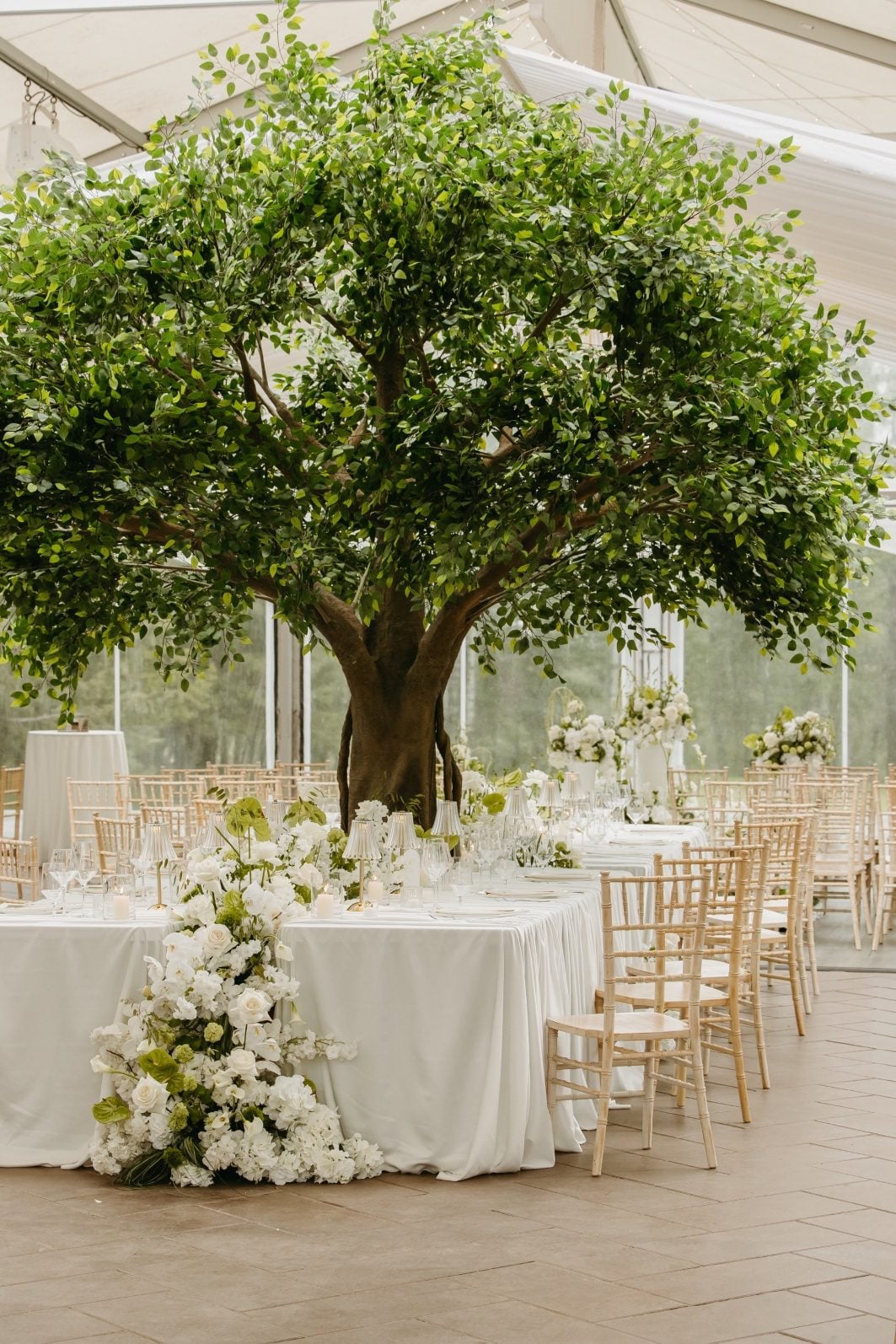 White and Green Wedding Flowers Waterfall The large feature table with the artificial tree from Copper Cloud bursting from the centre and full floral arrangements running down the middle and sides to water flow over the edges of the table.