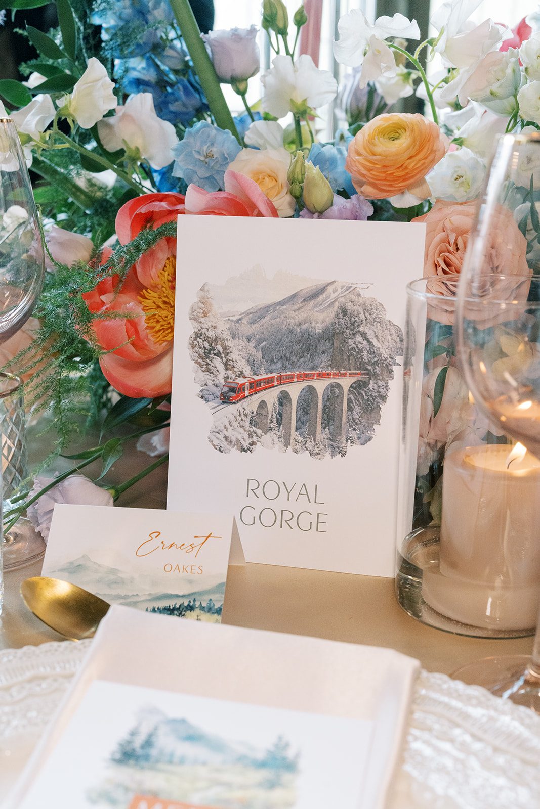 Lottie Travel inspired wedding table card featuring Royal Gorge surrounded by colourful garden inspired flowers.