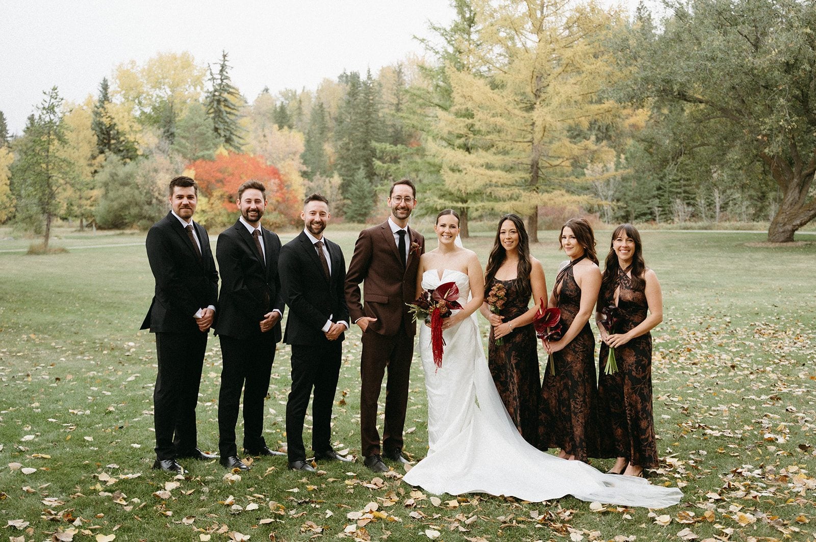 Andi + Logan Fall wedding party in black, brown and white with coordinated burgundy bouquets and sculptural floral details.