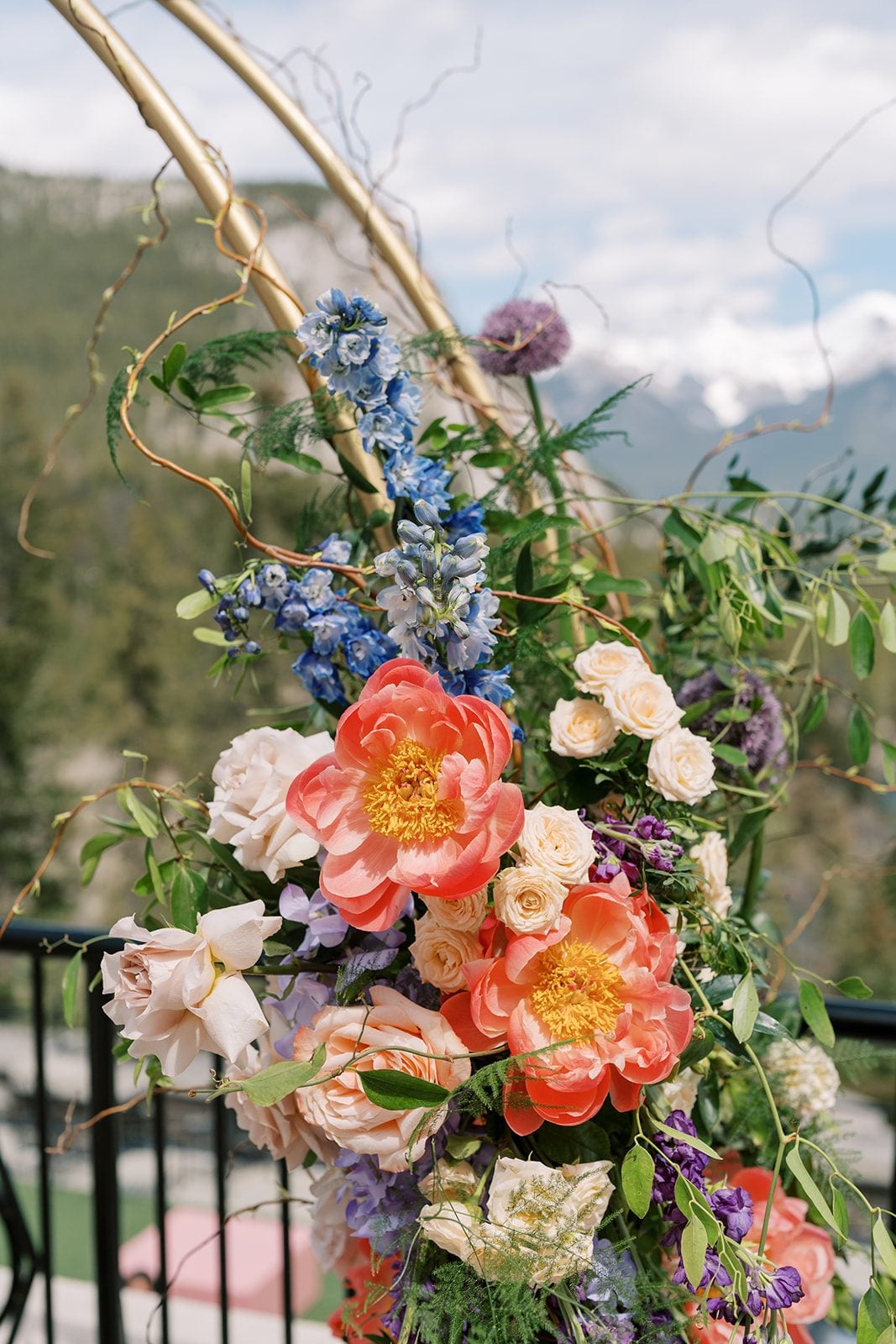 Lottie Colourful garden inspired wedding arch with coral peonies, blue delphinium and greenery overlooking the Rocky Mountains.