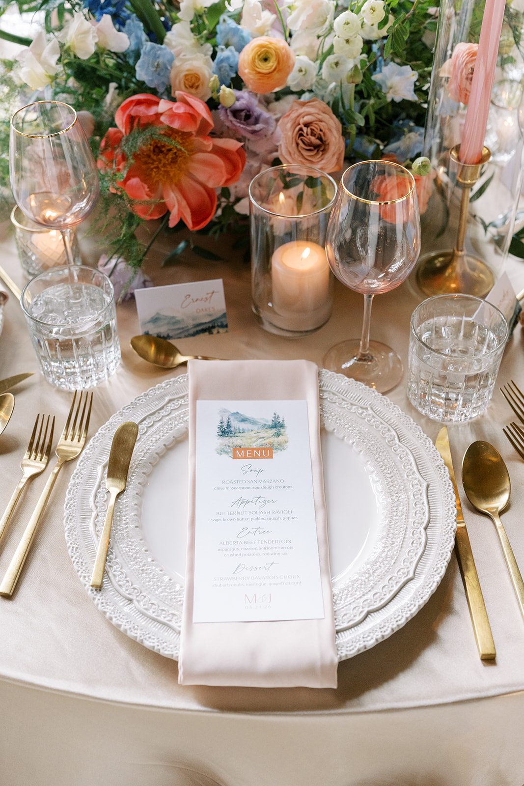 Lottie Elegant Fairmont Banff Springs wedding place setting with gold flatware, blush napkin and colourful garden flowers.