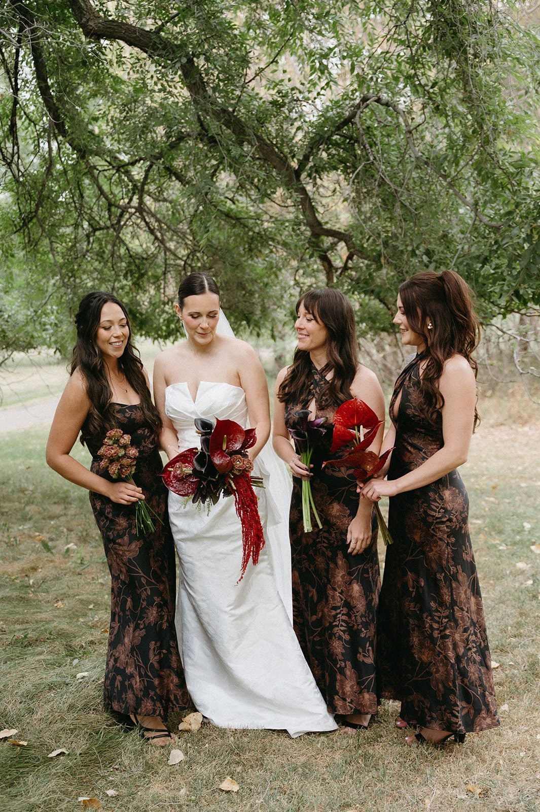 Andi + Logan Bride and bridesmaids in brown floral dresses carrying rich burgundy fall wedding bouquets.