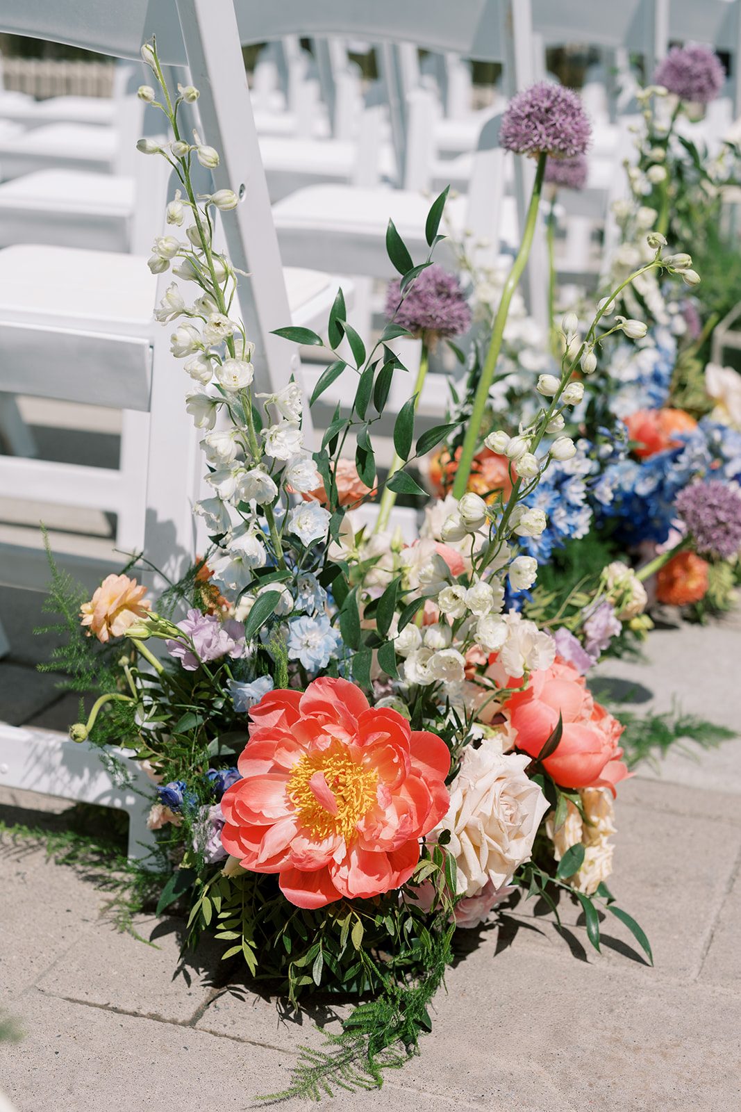 Lottie Colourful Fairmont Banff Springs wedding aisle flowers with coral peonies, blue delphinium, roses and purple allium.