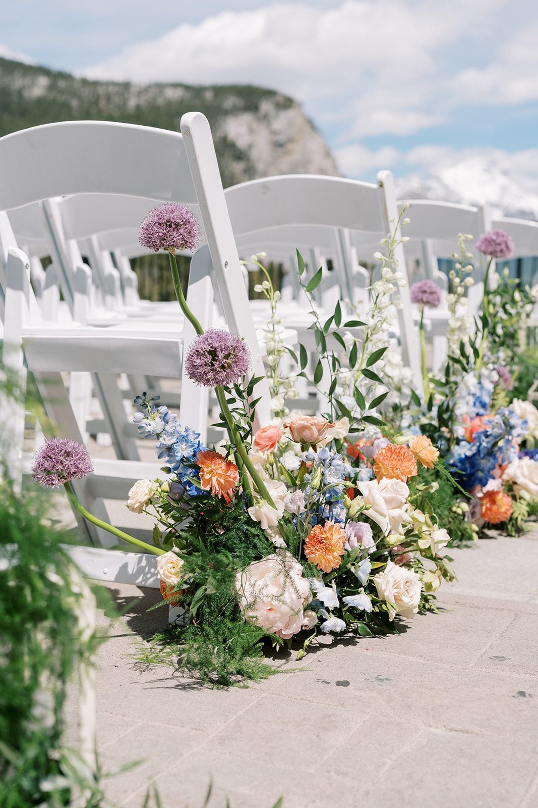 Lottie Garden inspired wedding aisle arrangement with peonies, roses, delphinium and allium overlooking the Banff mountains.