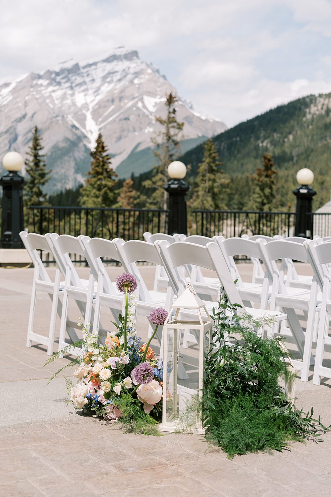 Lottie Colourful garden inspired ceremony flowers and white lanterns lining the aisle at a. Banff Springs wedding.
