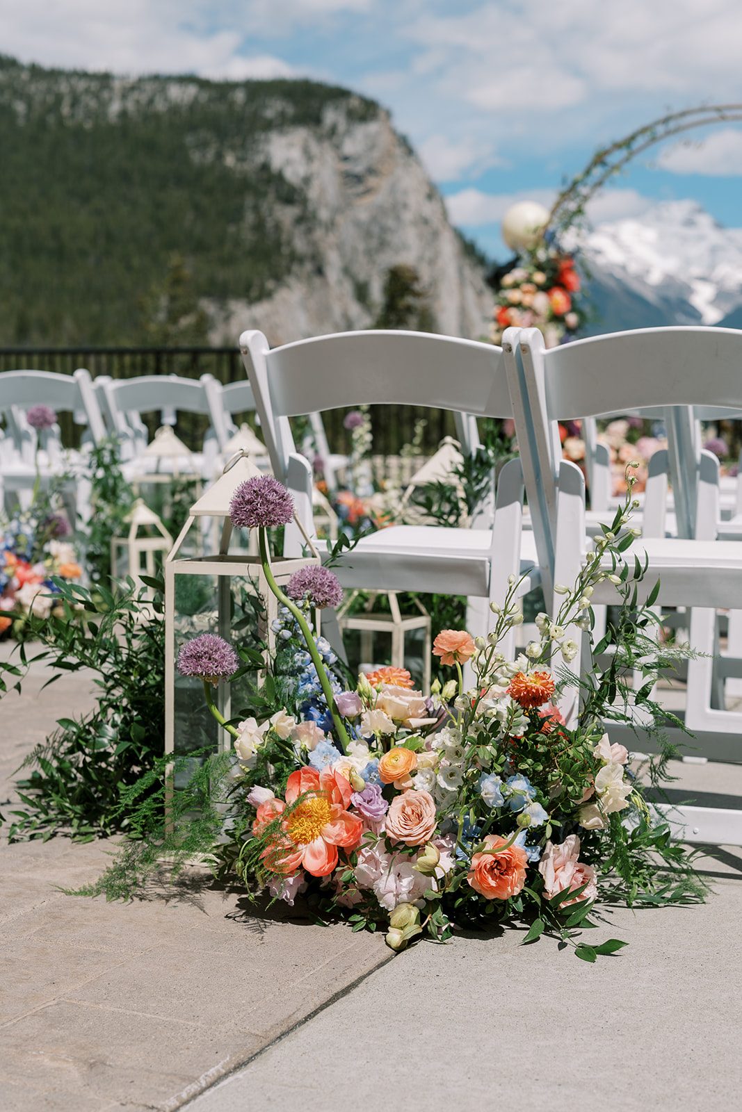 Lottie Garden Inspired wedding aisle flowers with coral peonies, roses, delphinium and purple allium at Fairmont Banff Springs.