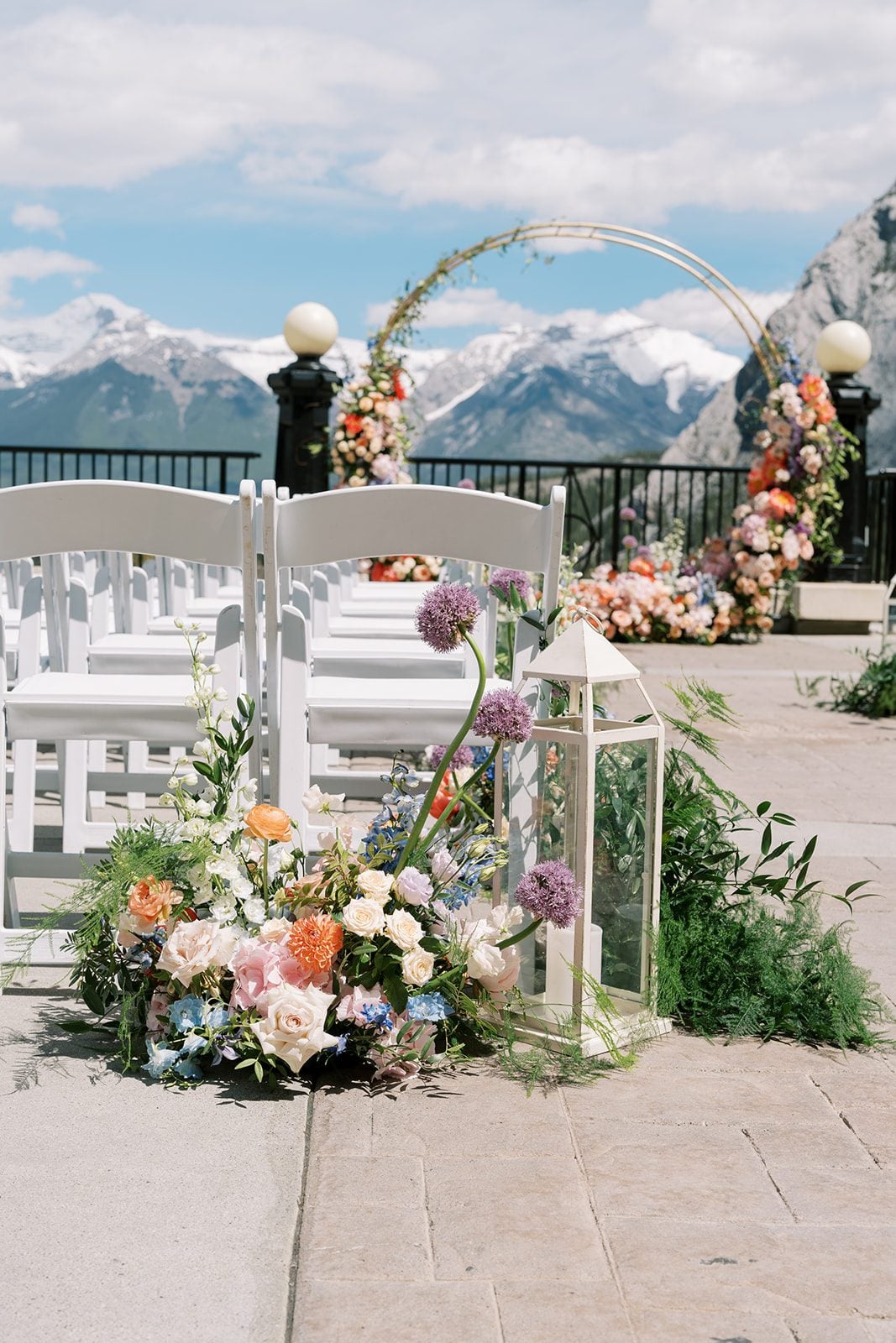 Lottie Fairmont Banff Springs wedding ceremony with colourful garden flowers, white chairs and panoramic Rocky Mountain views.